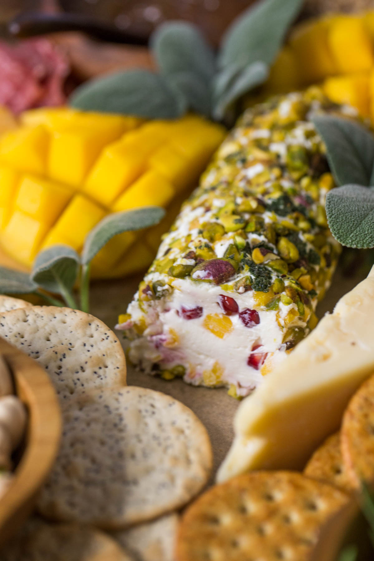 Close up view of Pistachio Crusted Cheese Log displayed as part of a charcuterie.