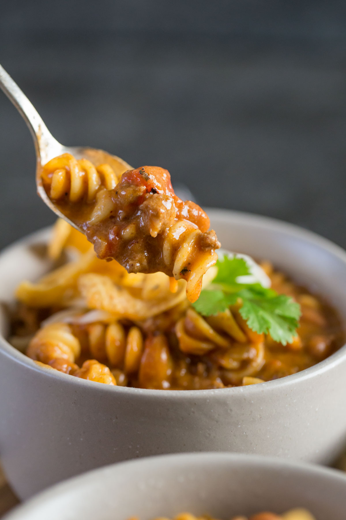 A spoonful of Beef Queso Chili in front of a bowl. 
