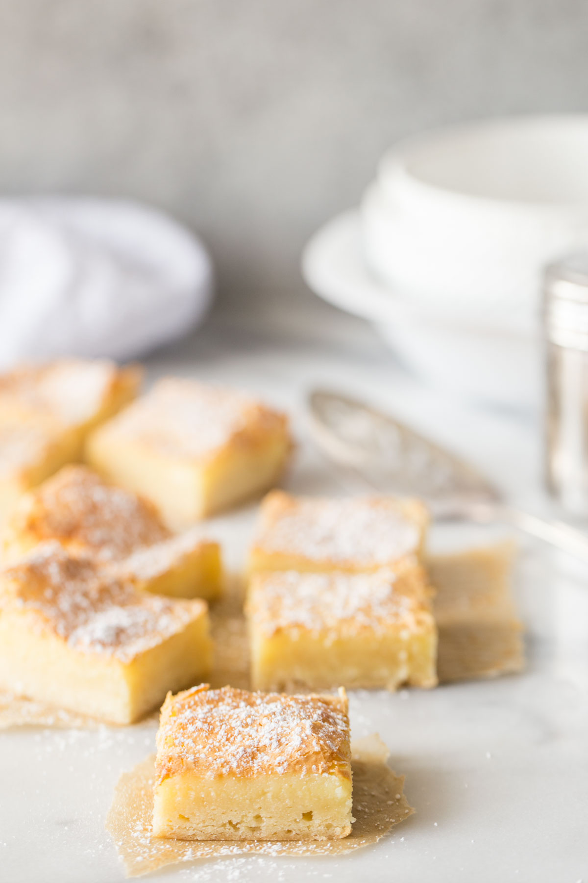 Gooey Butter Bars without cake mix cut into bars on a white marble background.