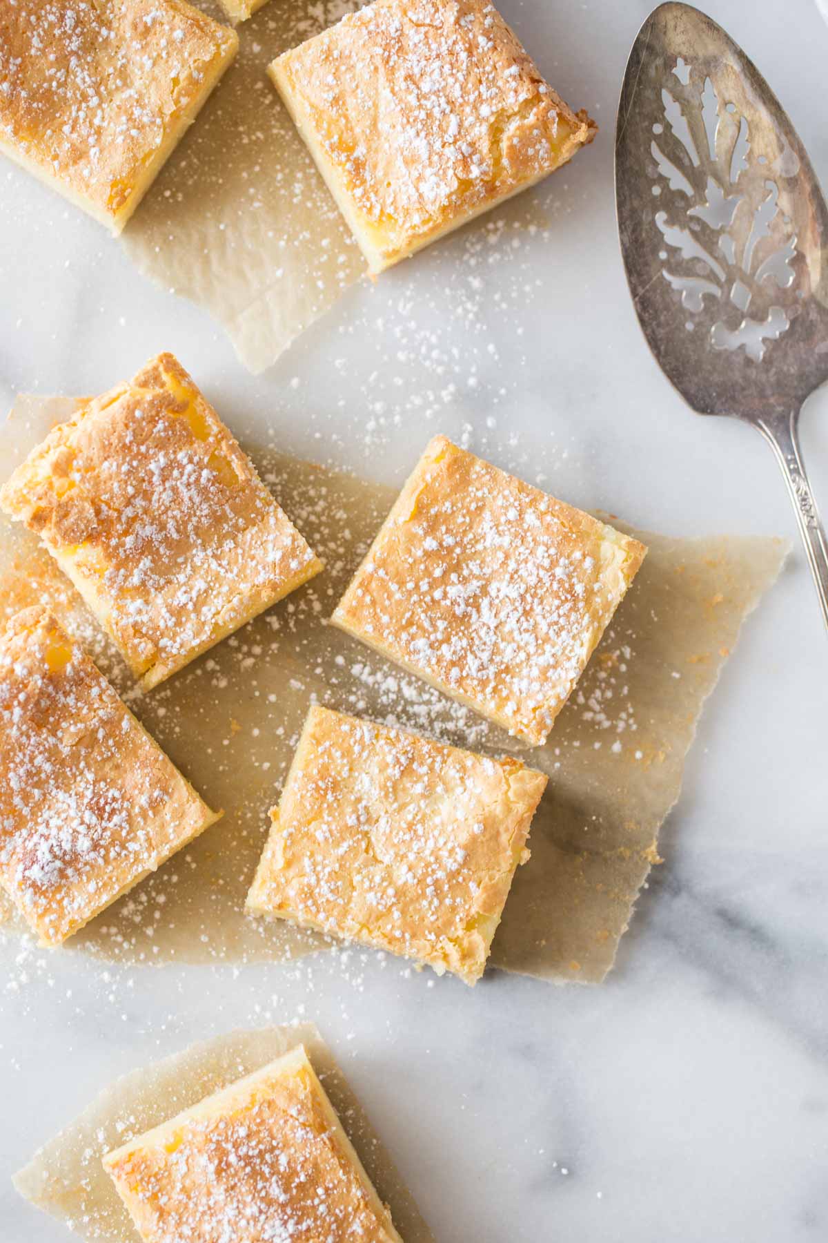 Overhead view of Gooey Butter Bars without cake mix cut into squares on a marble background.