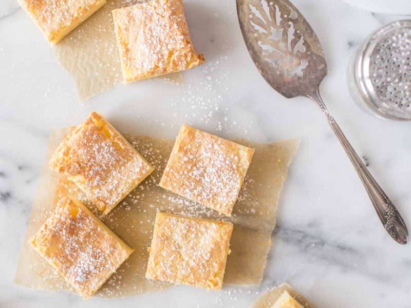 Overhead shot of Gooey Butter Bars cute into squares on a marble background.