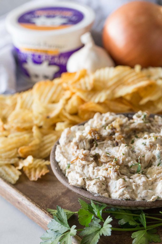 Bowl of Roasted Garlic and Caramelized Onion Dip on a platter with chips.