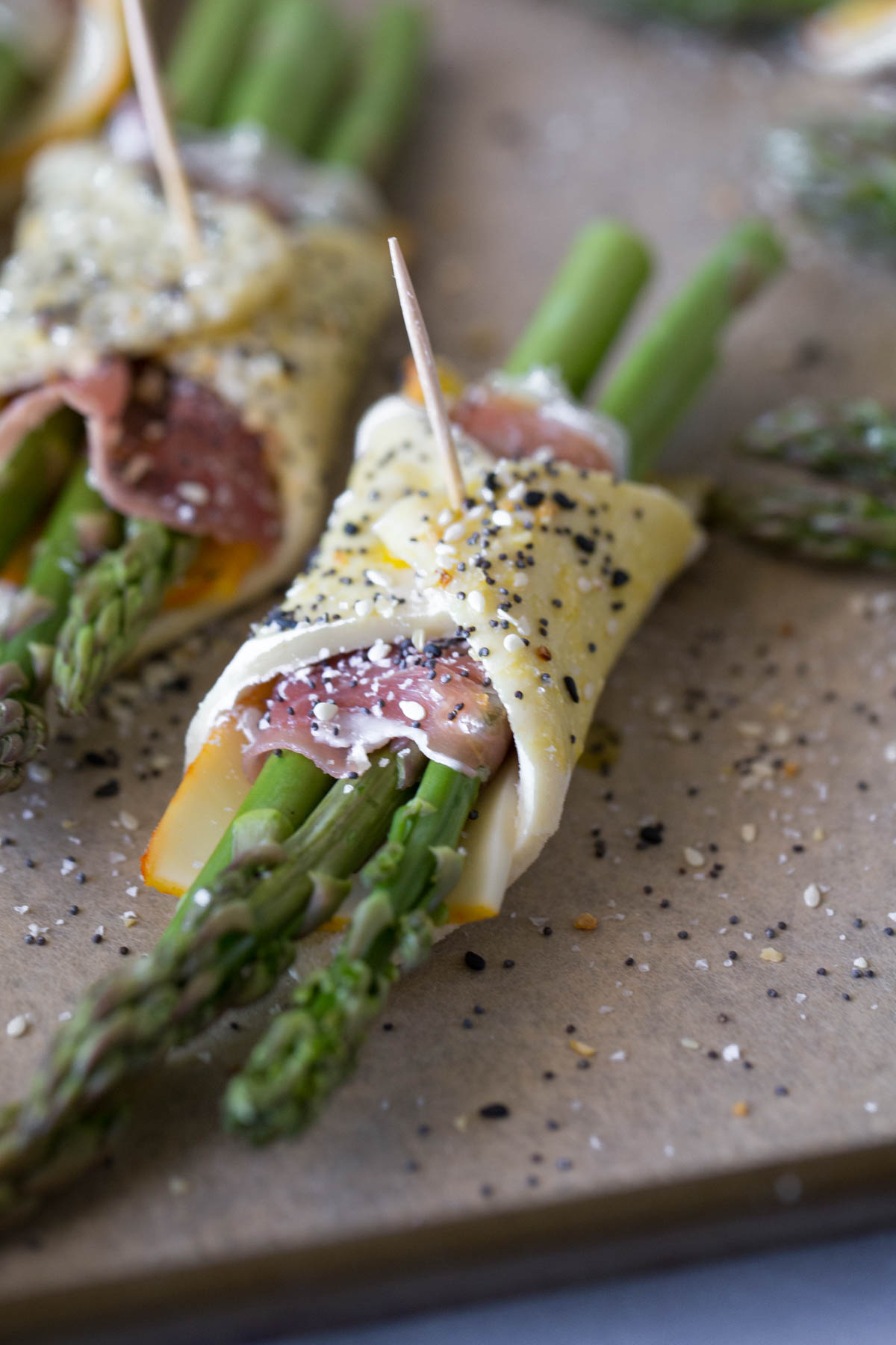 Close up view of uncooked asparagus bundles on parchment paper. 