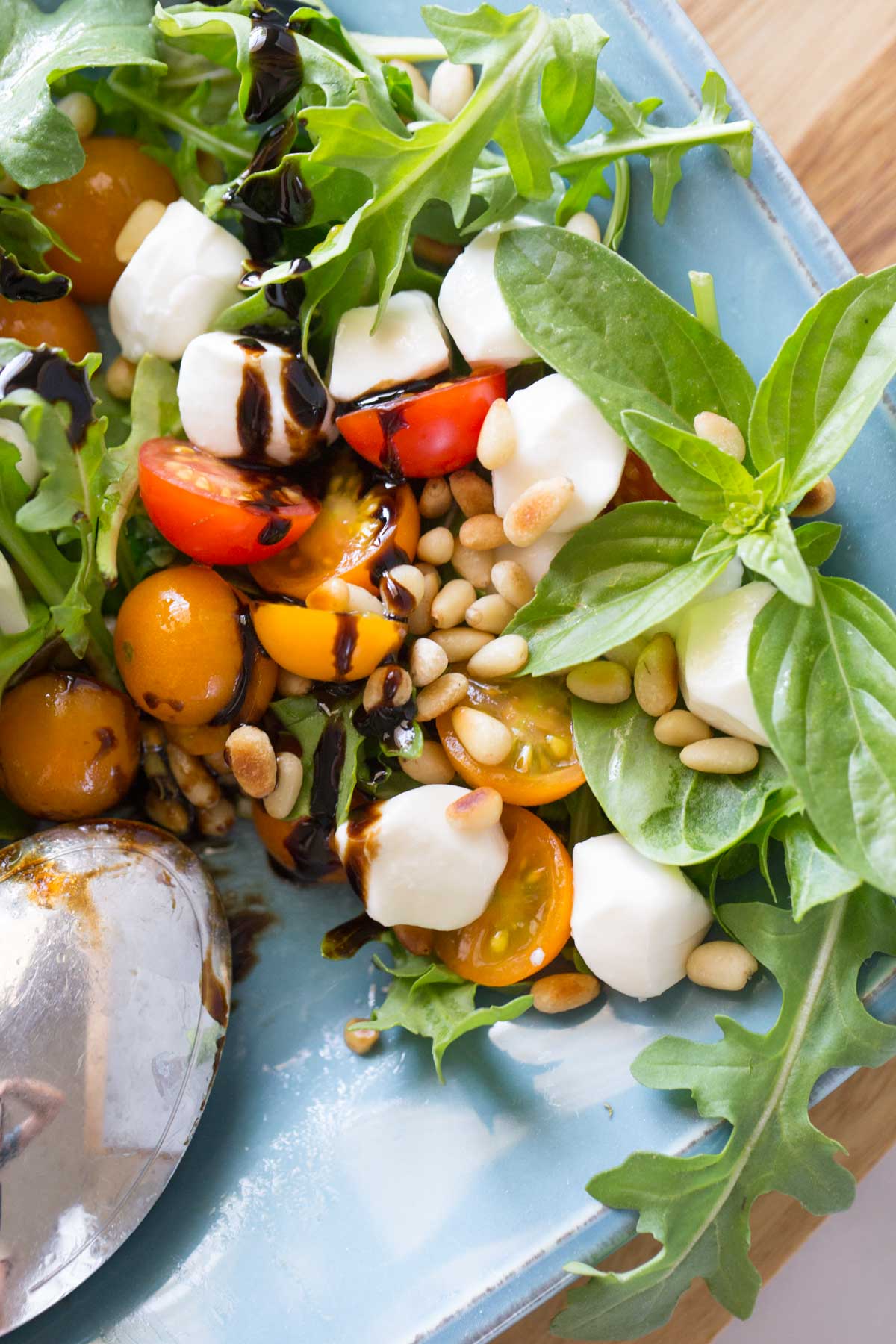 Close up view of Sungold Caprese Salad with a drizzle of balsamic glaze on a blue platter.