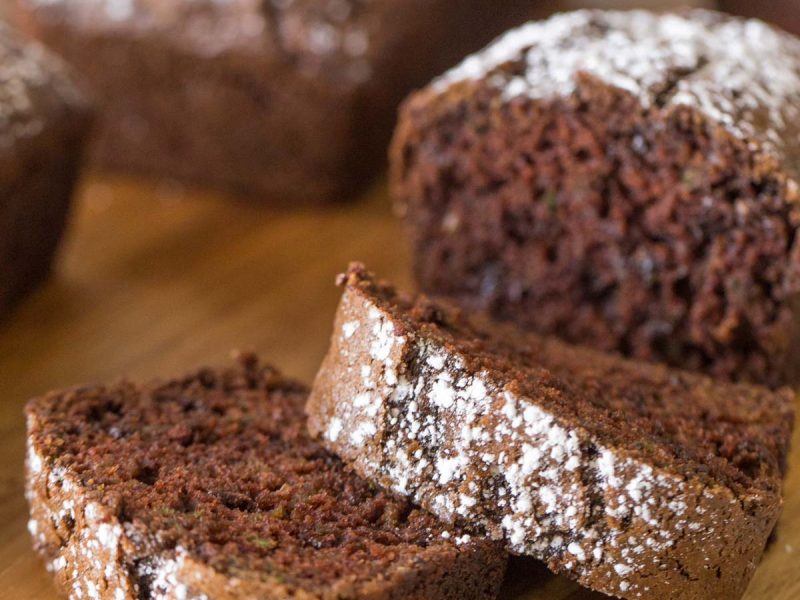 Slices of Chocolate Zucchini Bread on a wooden cutting board.