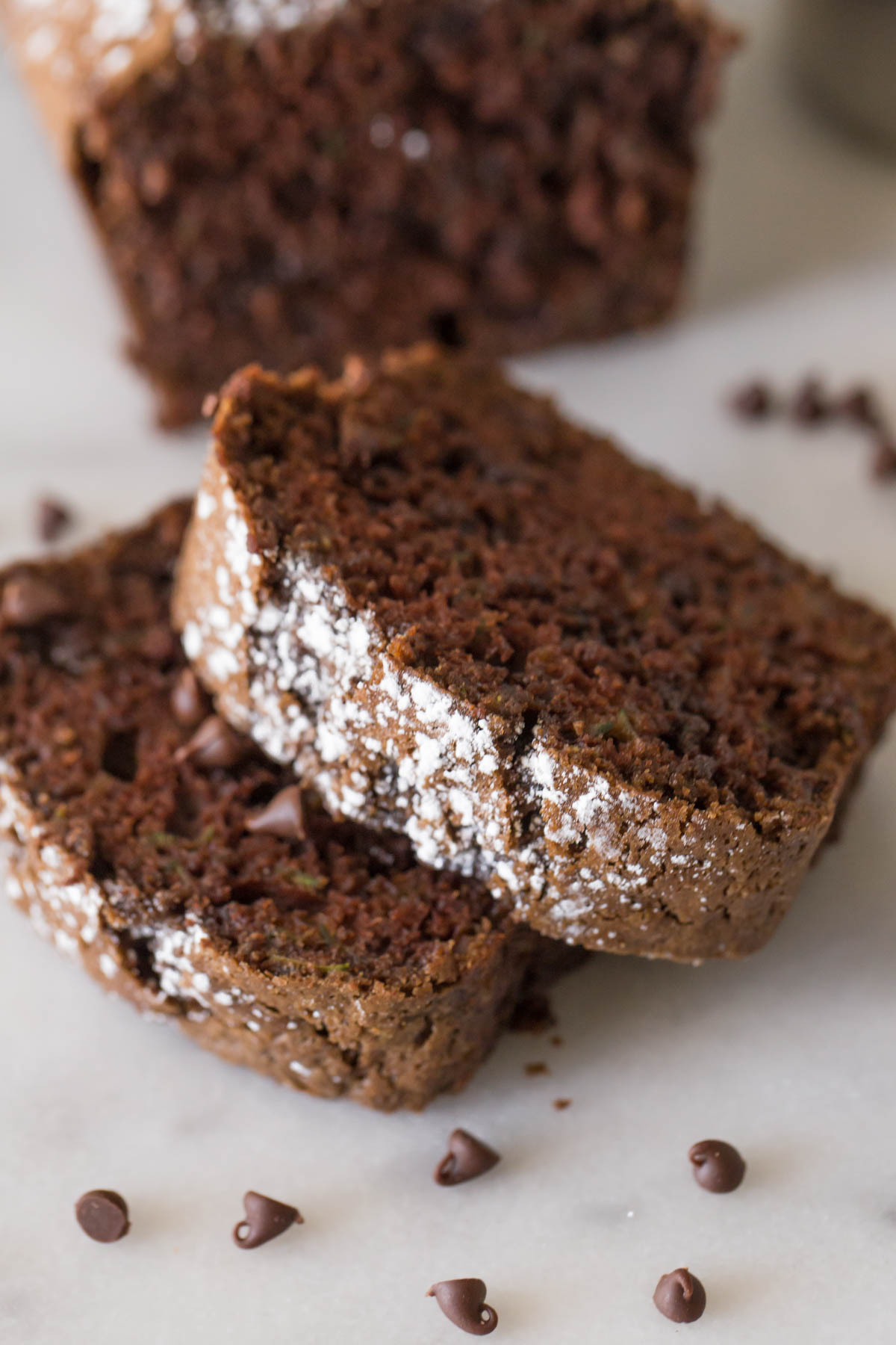 Close up view of slices of Chocolate Zucchini Bread on a marble background.