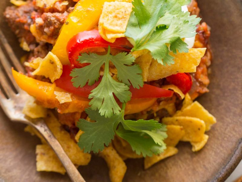 Overhead view of Unstuffed Pepper Skillet in a bowl topped with Fritos, cilantro and sour cream.