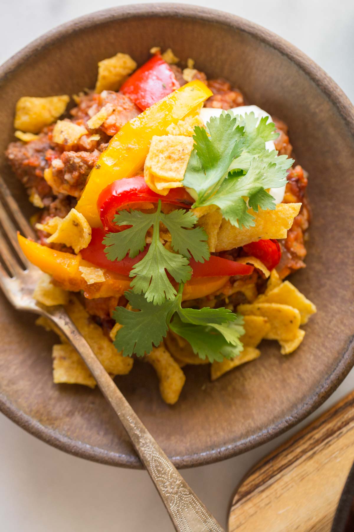 Overhead view of Unstuffed Pepper Skillet in a bowl topped with Fritos, cilantro and sour cream.