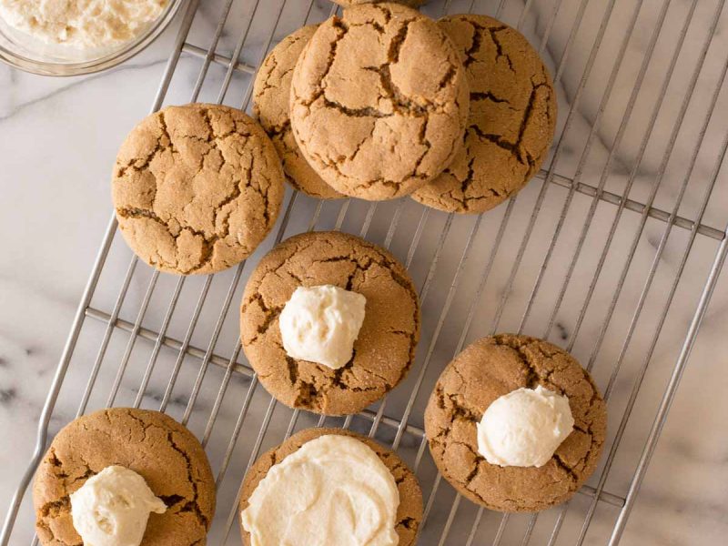 Bakery Style Molasses Cookies on a white marble board in the process of frosting.
