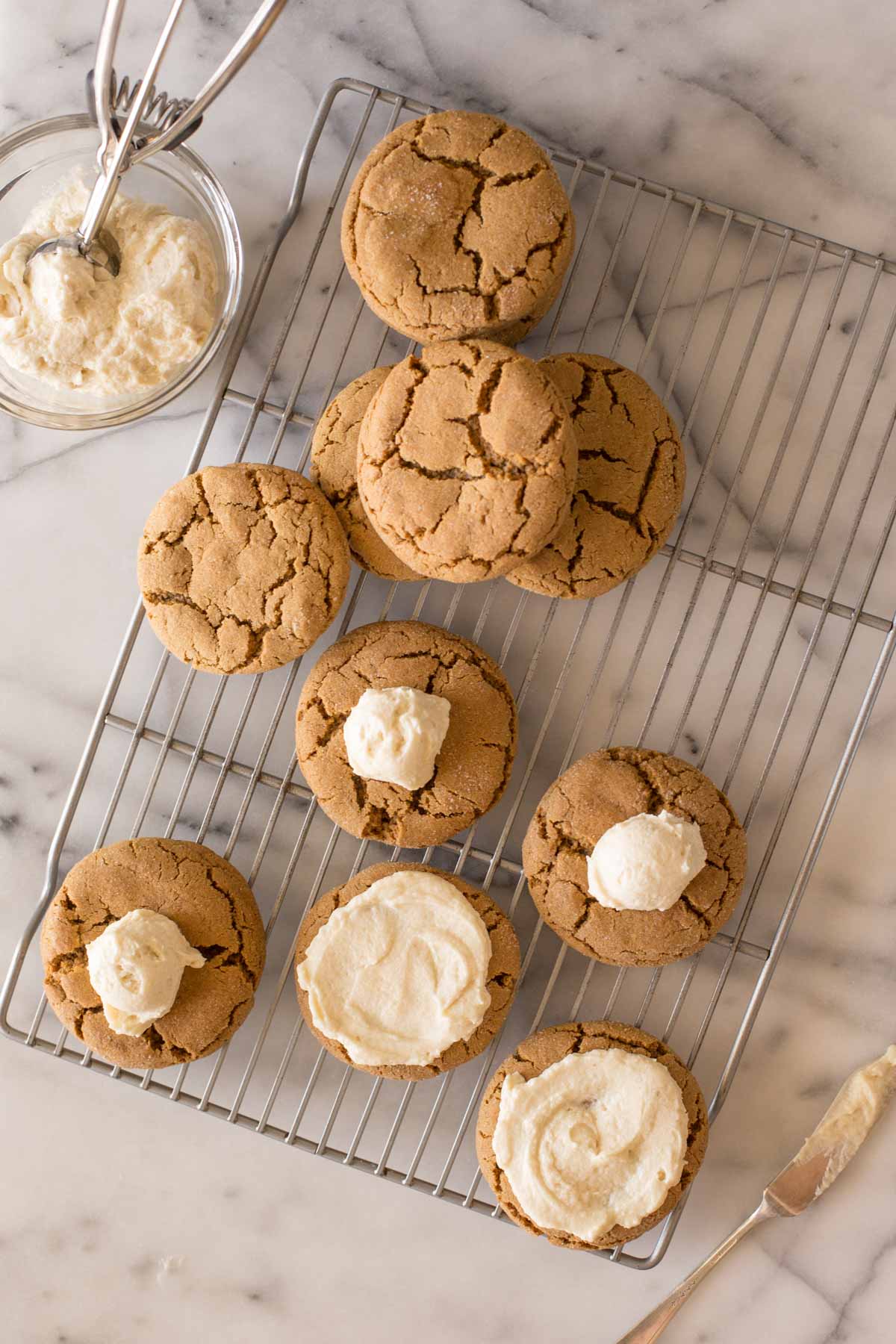 Bakery Style Molasses Cookies on a white marble board in the process of frosting.