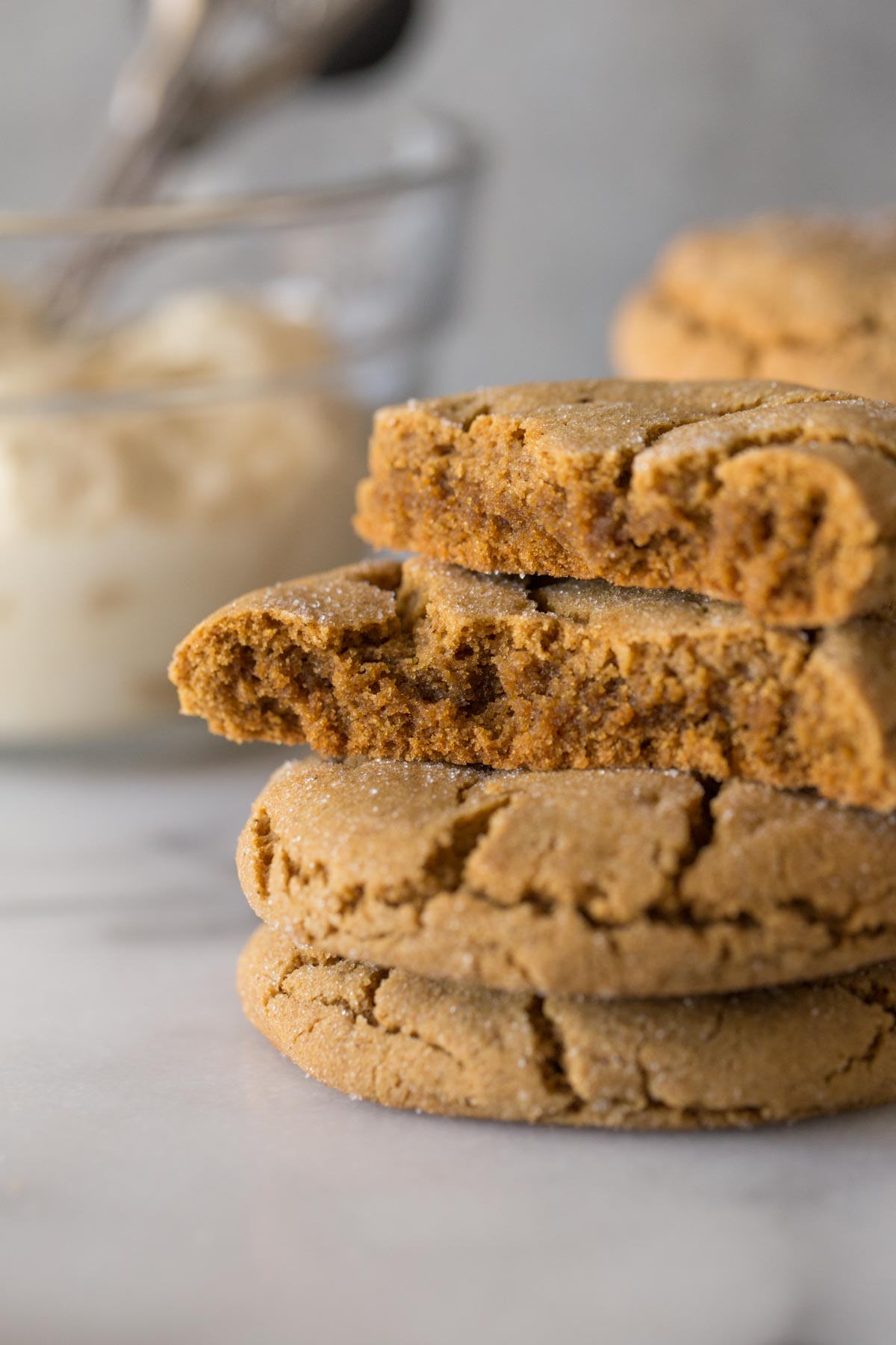 Close up view of halved Bakery Style Molasses Cookie stacked on a white marble board to show inside texture. 