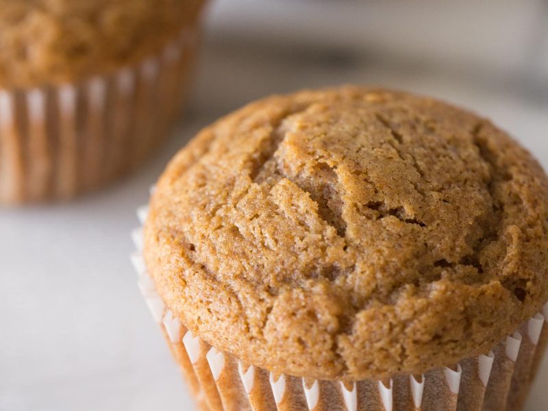 Close up view of the top of a Cinnamon Applesauce Muffin on a white background.