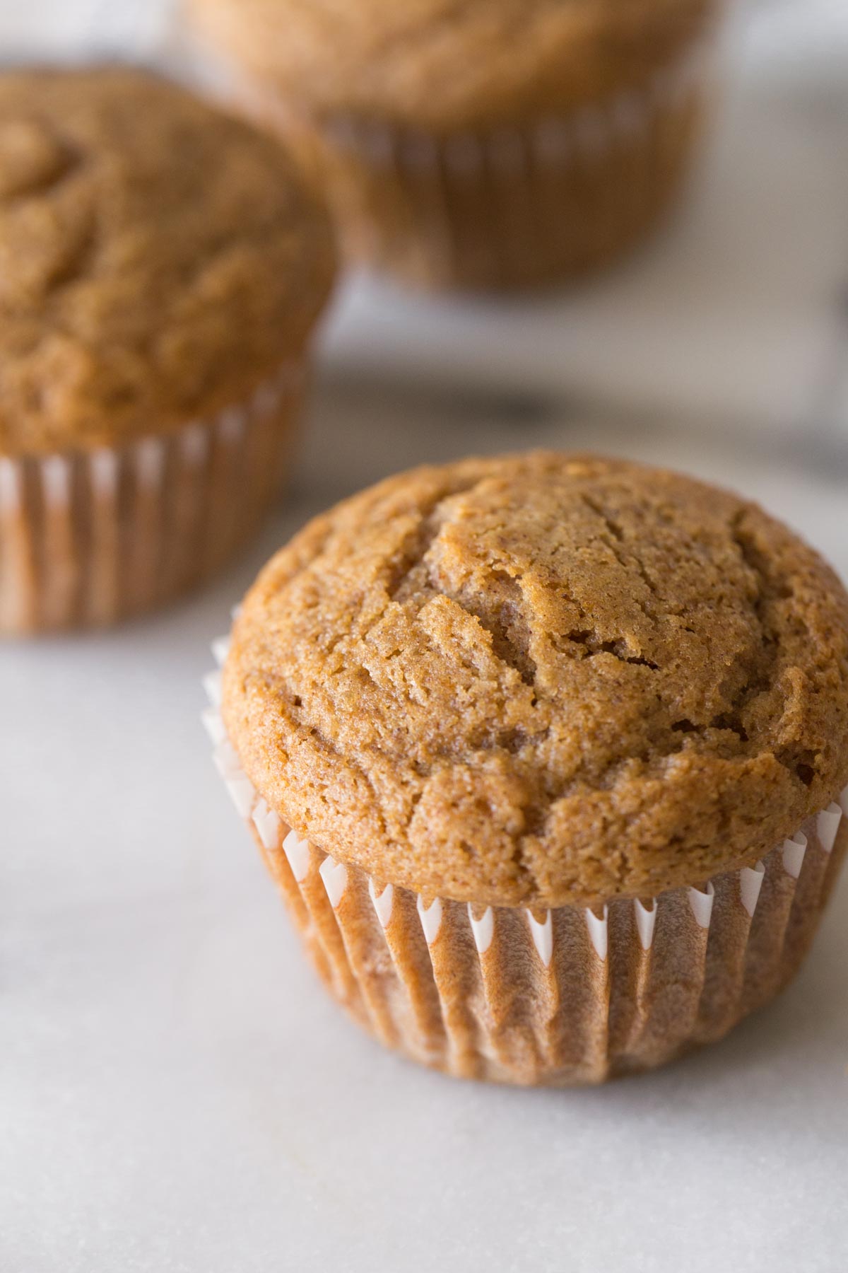 Close up view of the top of a Cinnamon Applesauce Muffin on a white background.