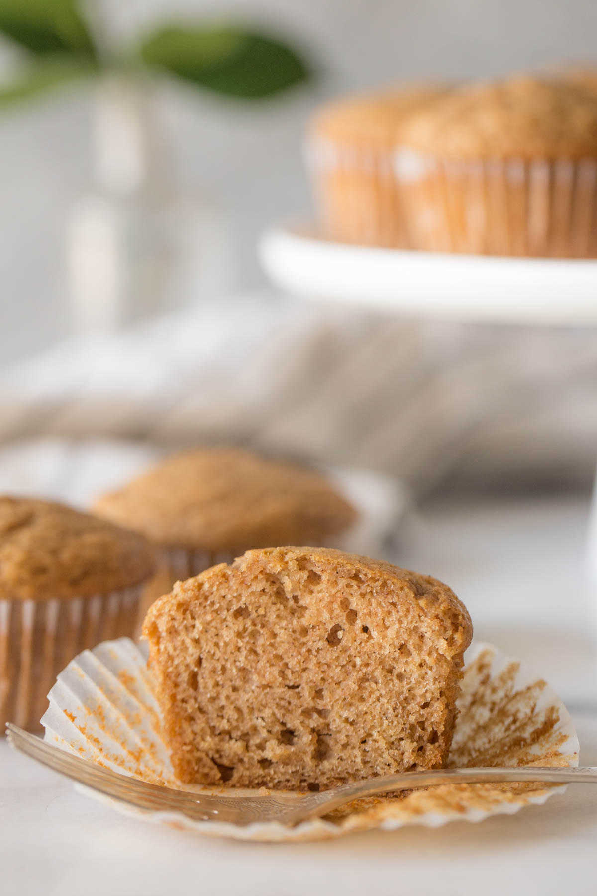 A close up view of a halved Cinnamon Applesauce Muffin on a white background.