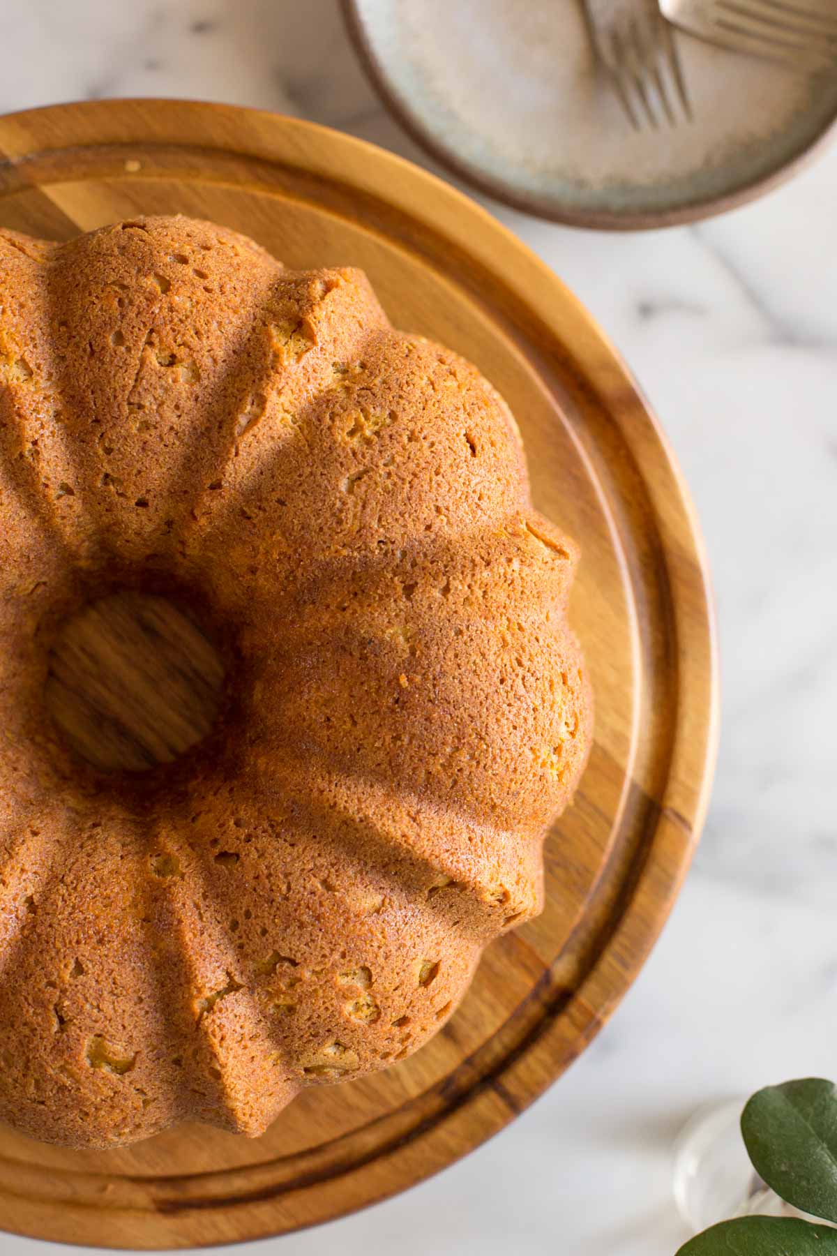 Overhead view of Apple Pumpkin Cake on a cake stand. with a white marble background.