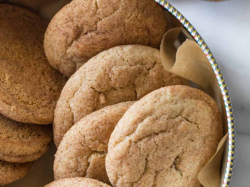 Overhead view of Super Soft Snickerdoodles in a cookie tin on a white marble background.