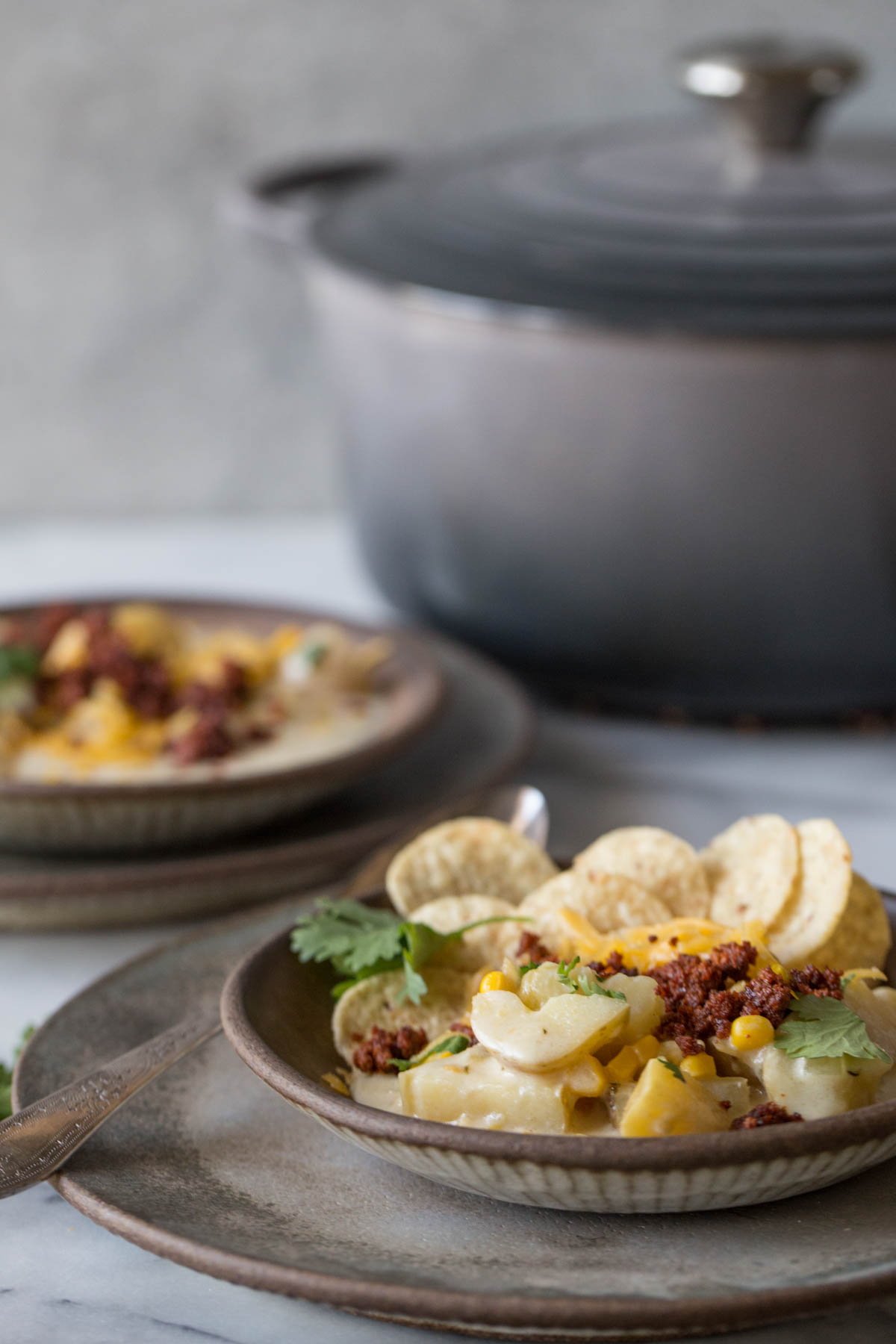 Up close shot of Creamy Corn Chowder With Chorizo in with a side of tortilla chips.