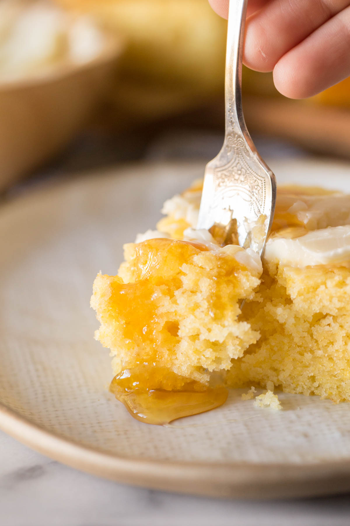 Fork cutting into a bar of Easy Homemade Cornbread on a white plate. 