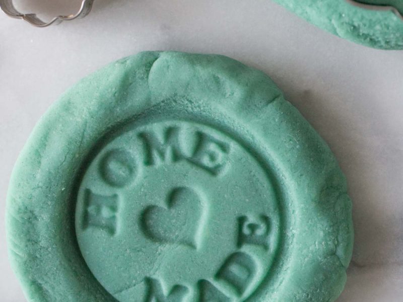 Blue homemade playdough with the words home made stamped into it.