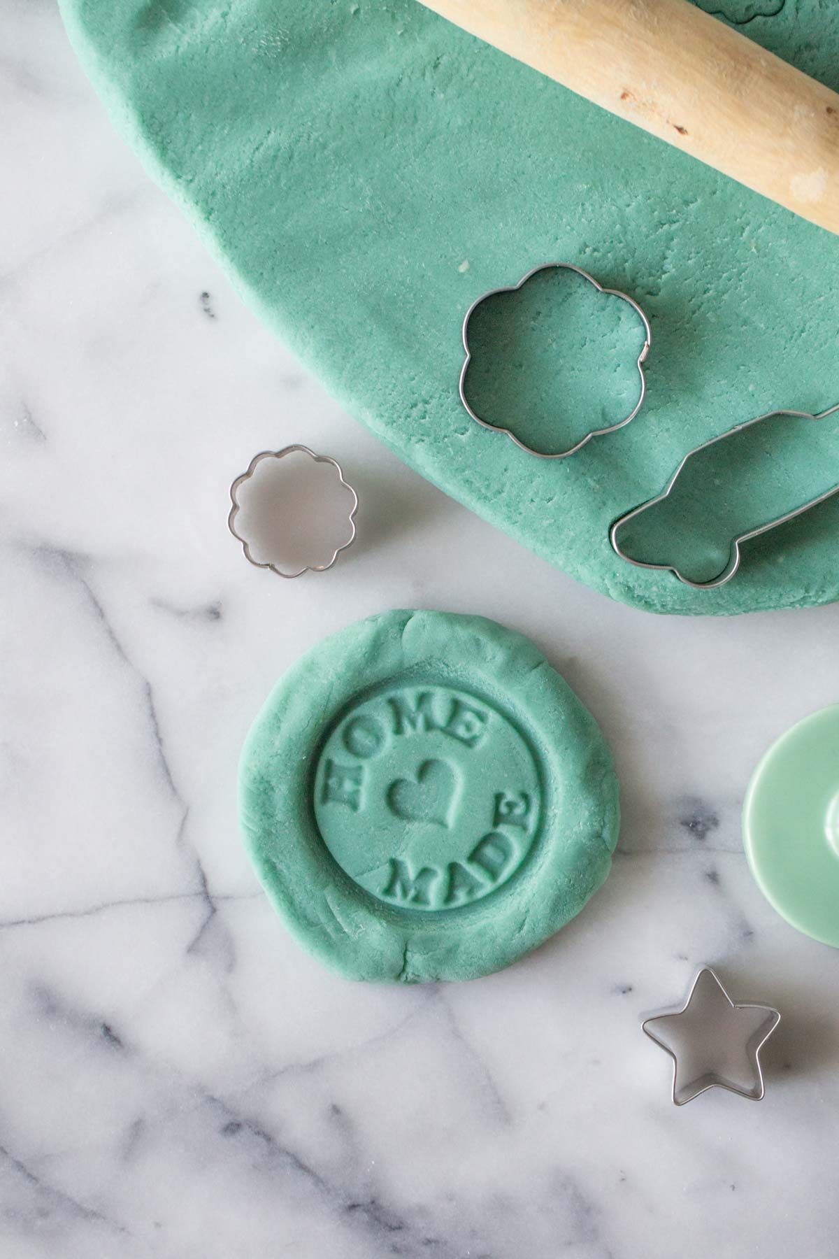 Overhead view of homemade playdough on a marble board with cutters.