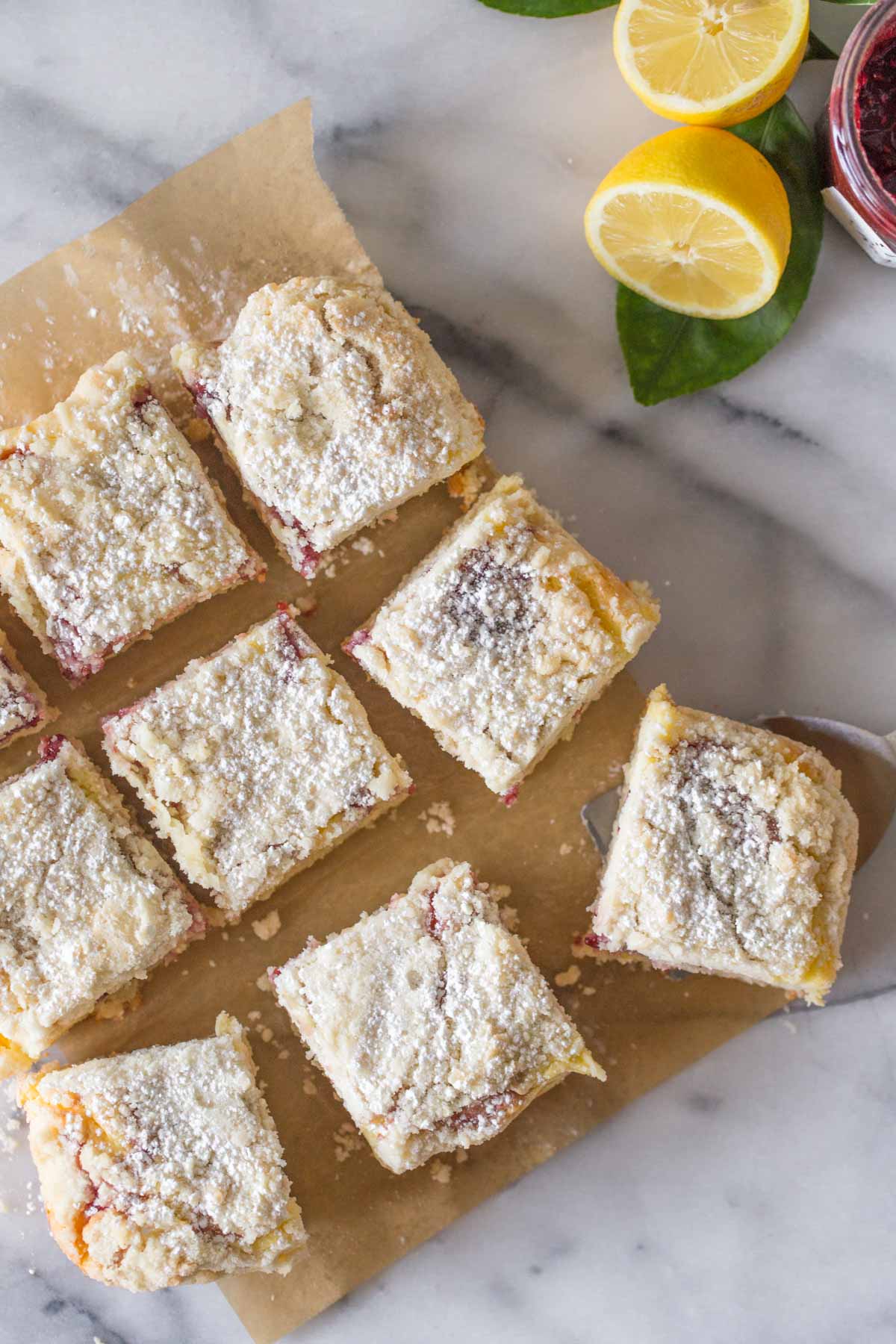 Overhead shot of cut pieces of Lemon Raspberry Cream Cheese Coffee Cake on a piece of parchment paper on a marble slab.