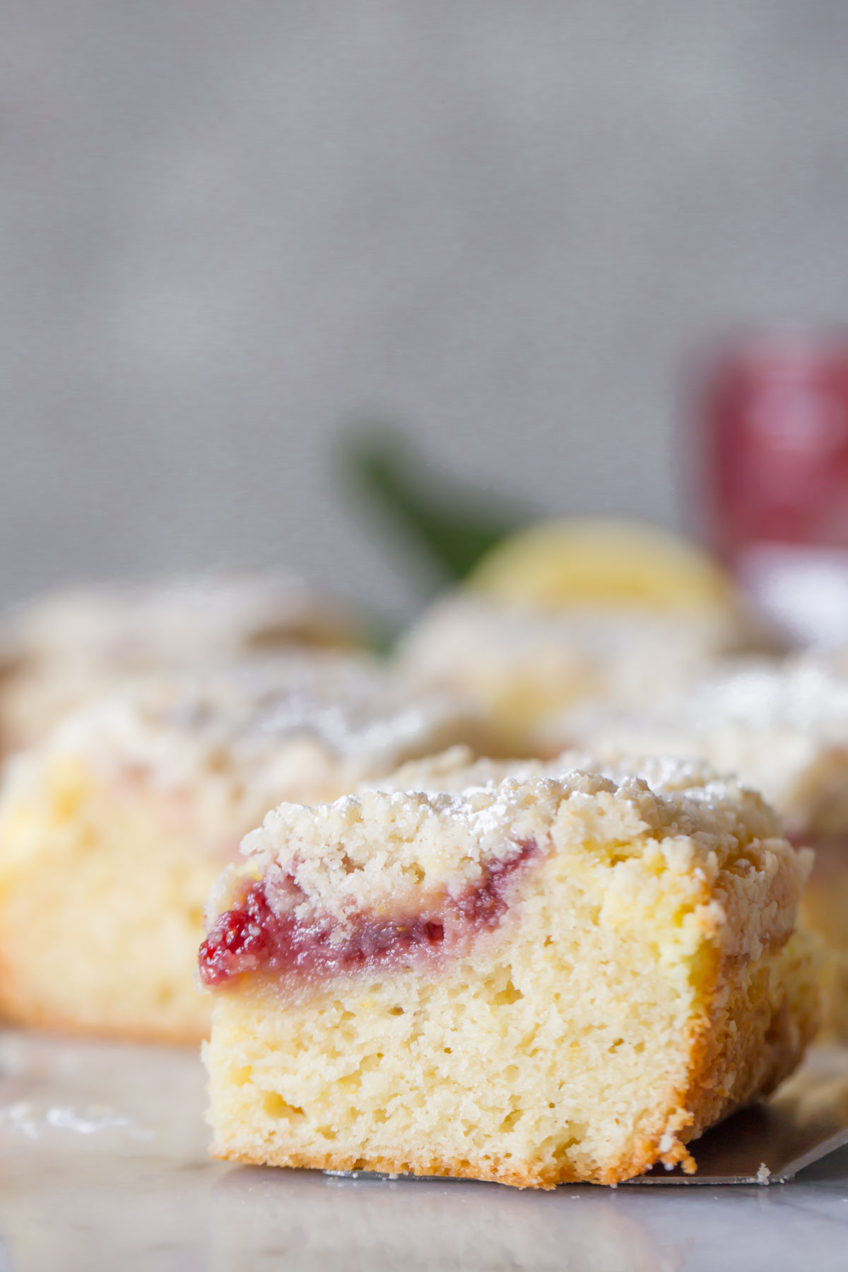 Close up shot of sliced Lemon Raspberry Cream Cheese Coffee Cake on a marble background.