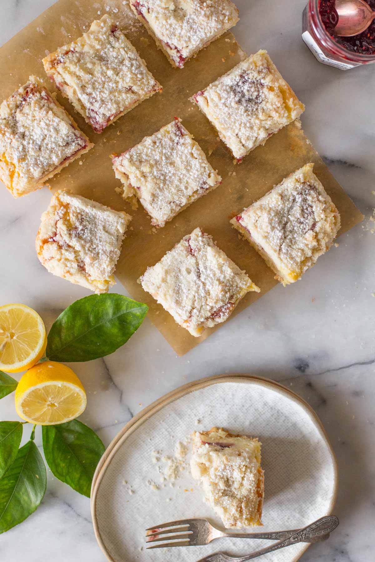 Overhead shot of cut pieces of Lemon Raspberry Cream Cheese Coffee Cake with fresh lemons.