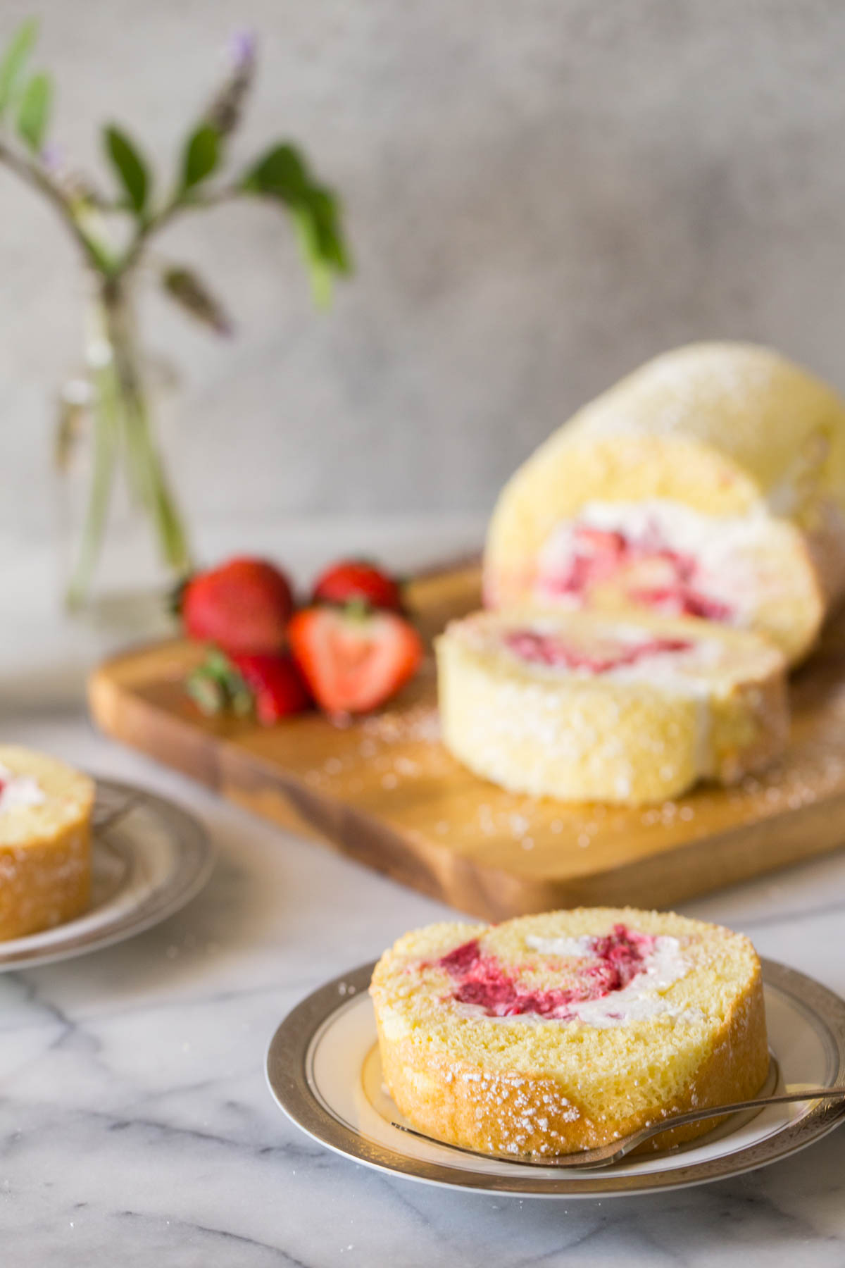 Sliced and served Vanilla Cake Roll on a grey background.