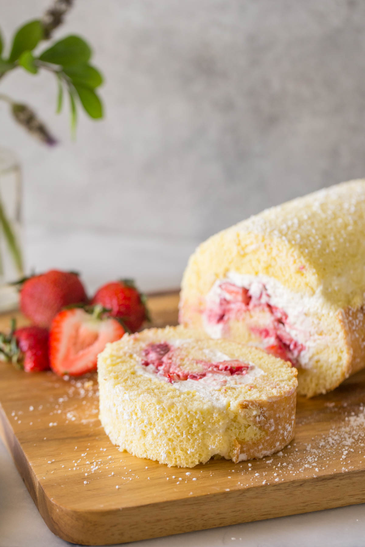 Overhead view of a sliced Vanilla Cake Roll on a wooden board.
