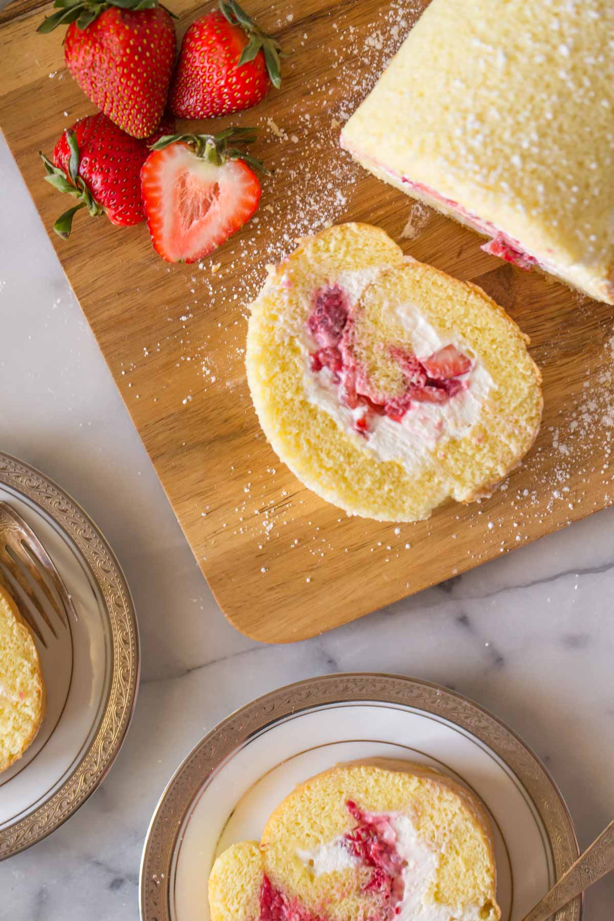 Overhead view of Vanilla Cake Roll on wooden cutting board.
