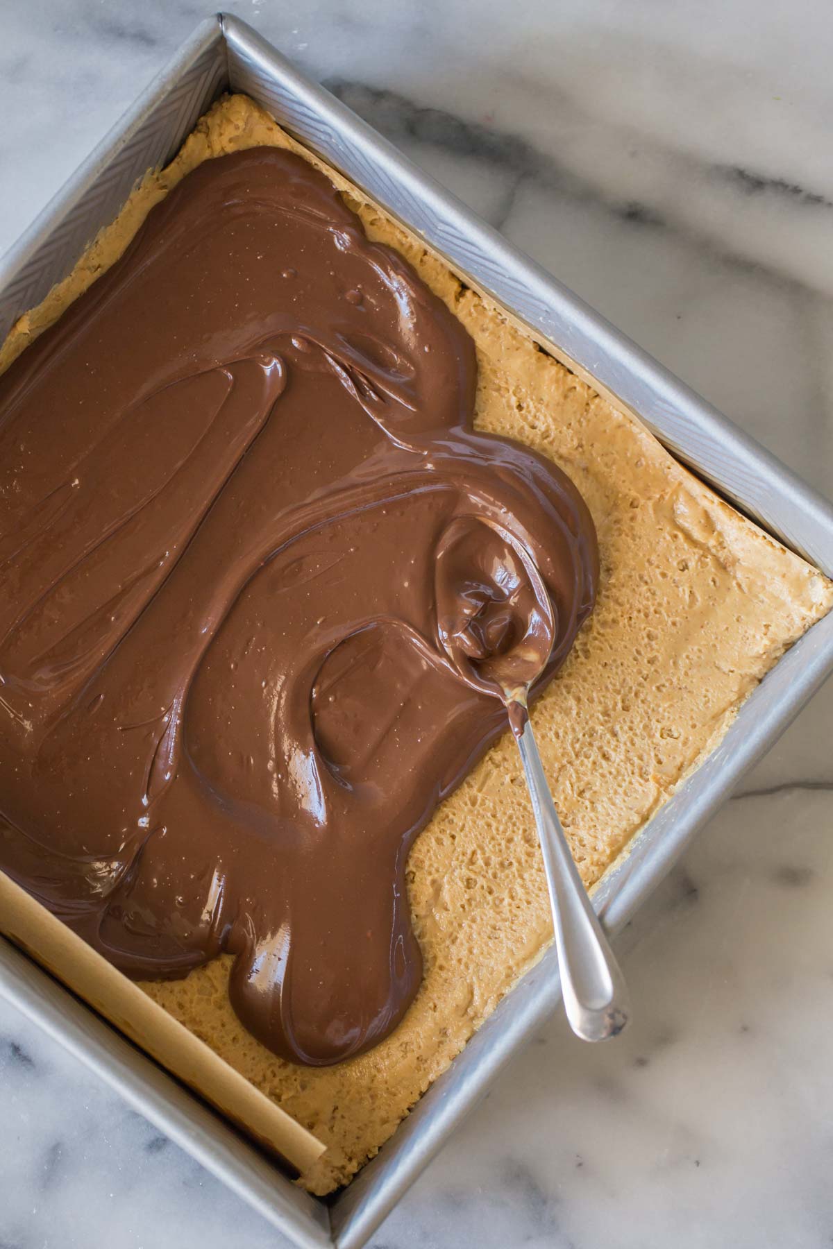 Overhead shot of melted chocolate spreading over the peanut butter layer. 