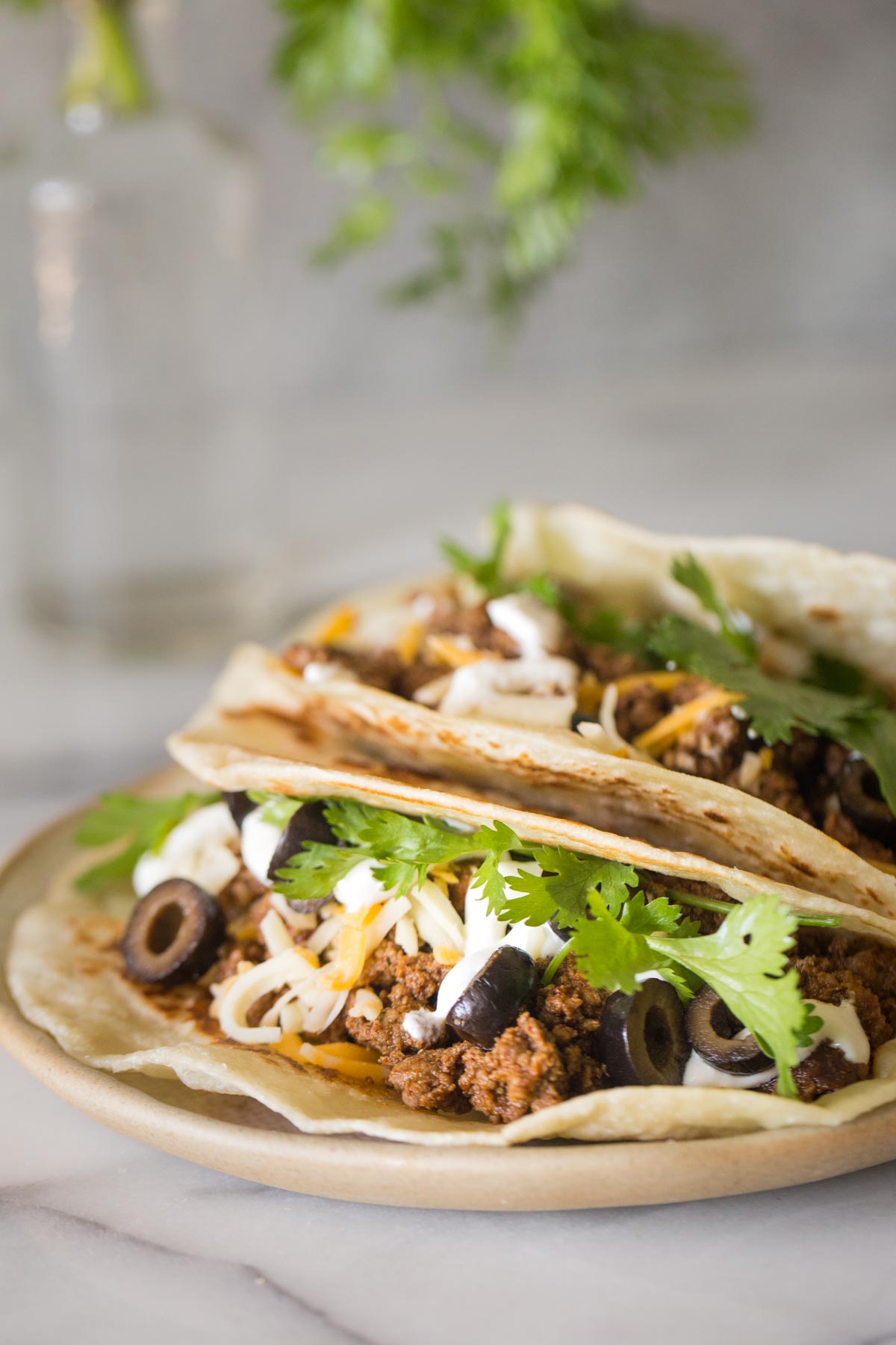 Close up shot of tacos with toppings and a grey background.