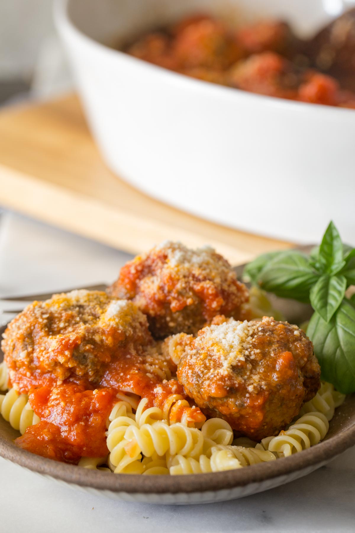 Easy Broiled Italian Meatballs served over rotini pasta in a bowl.