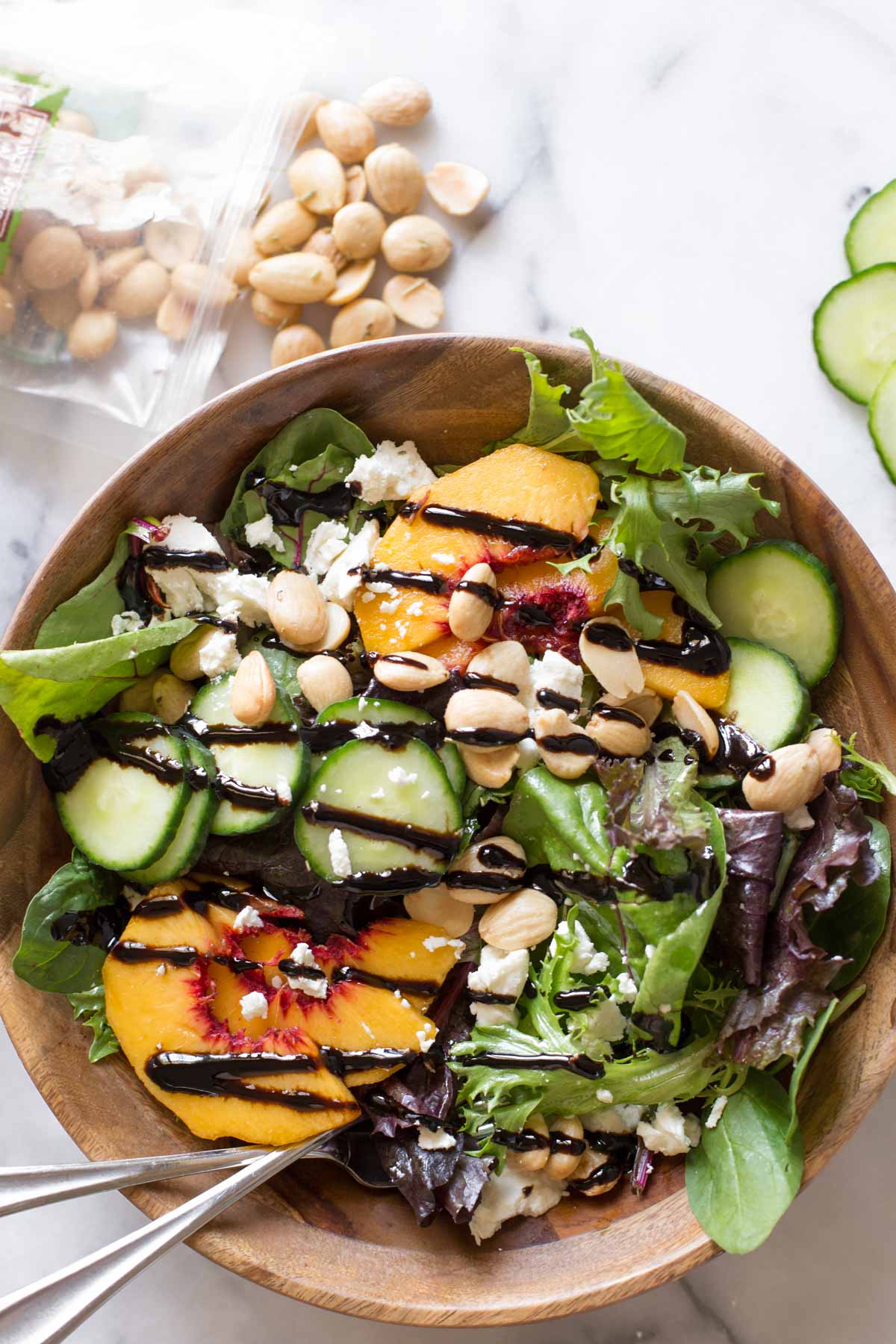 Overhead shot of Summer Peach Salad in a wood bowl on a marble background.
