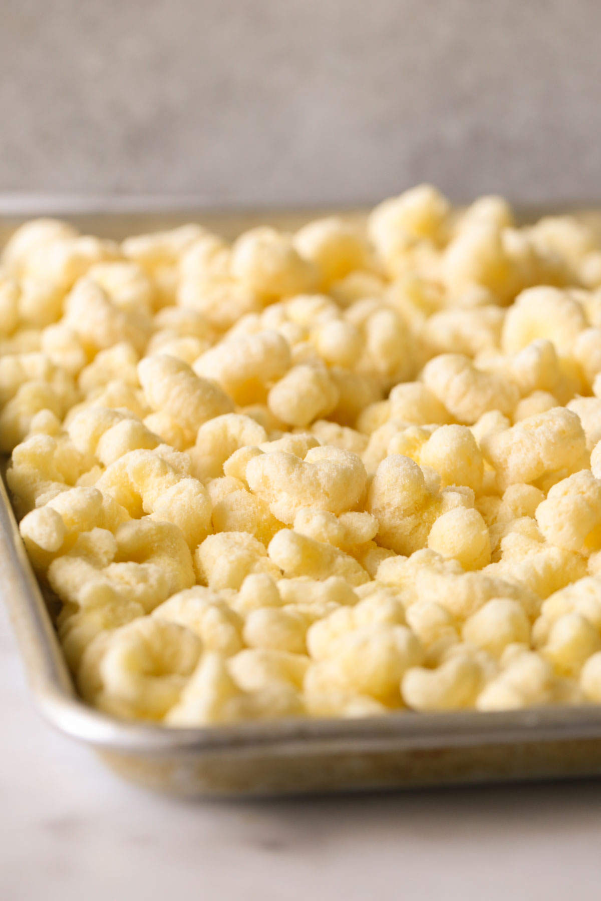 Close up shot of puffed corn on a rimmed baking sheet.  