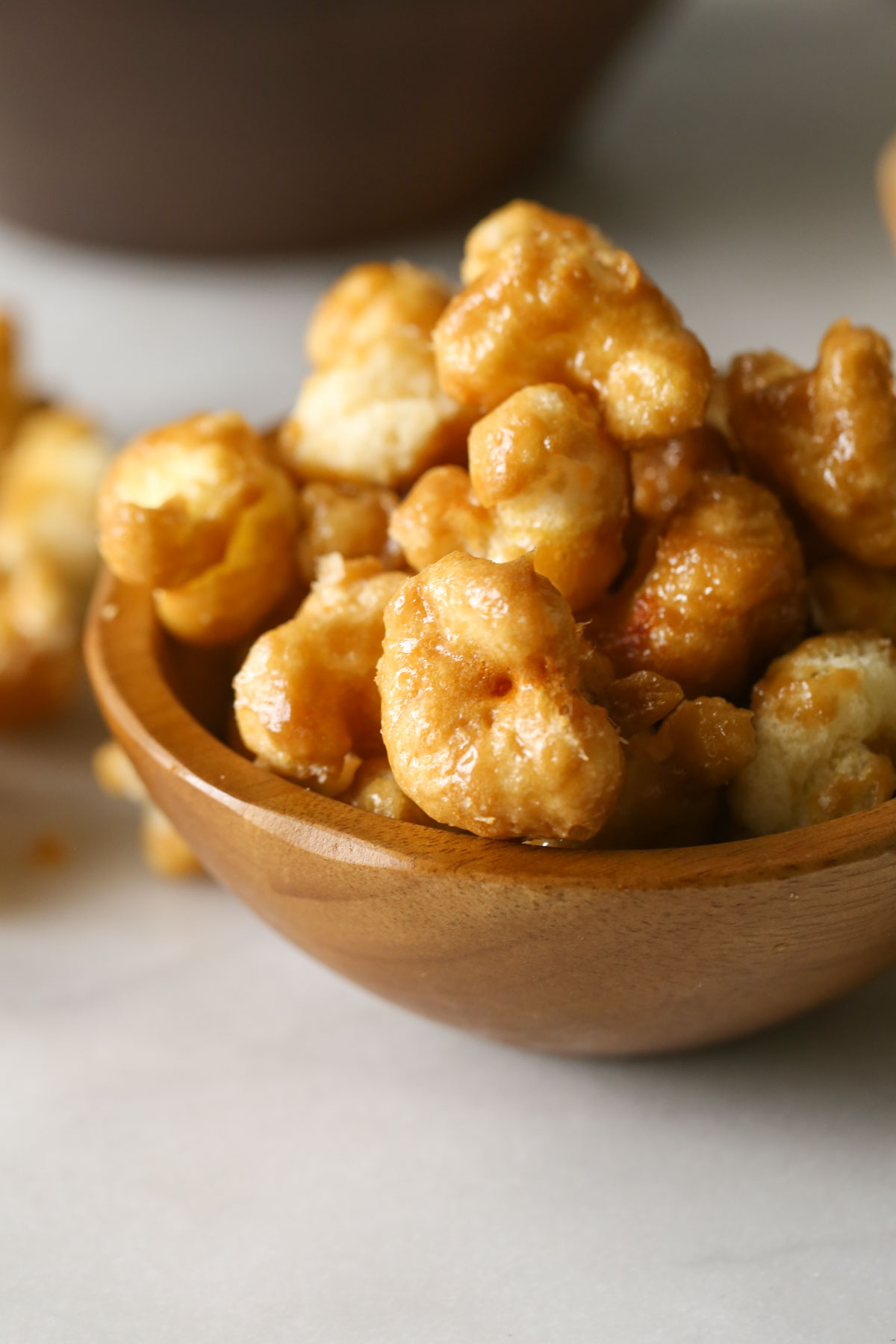 Close up shot of a small wood bowl full of Caramel Puff Corn.  