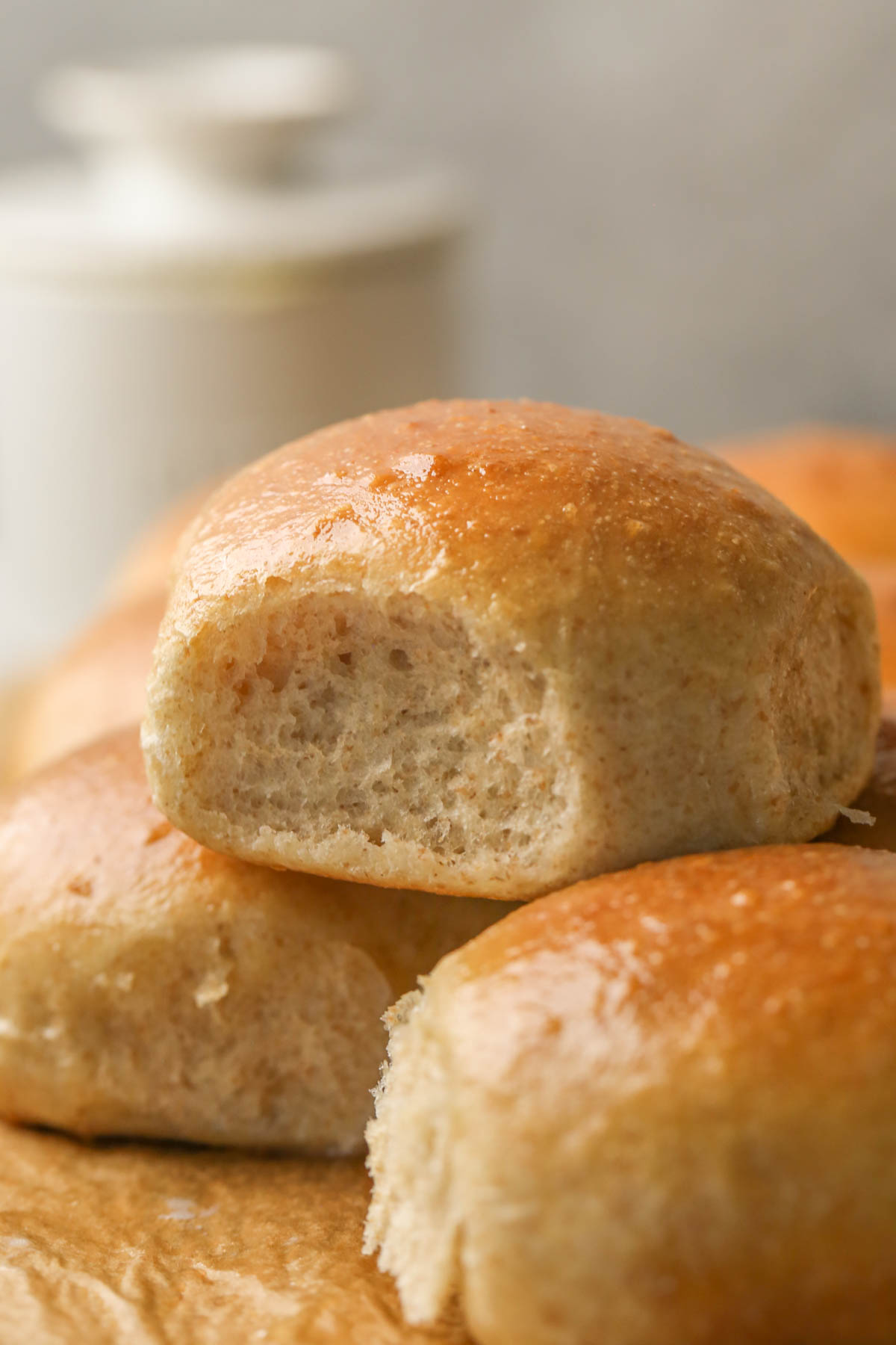Close up shot of an Overnight Honey Wheat Roll staked on top of other rolls.  