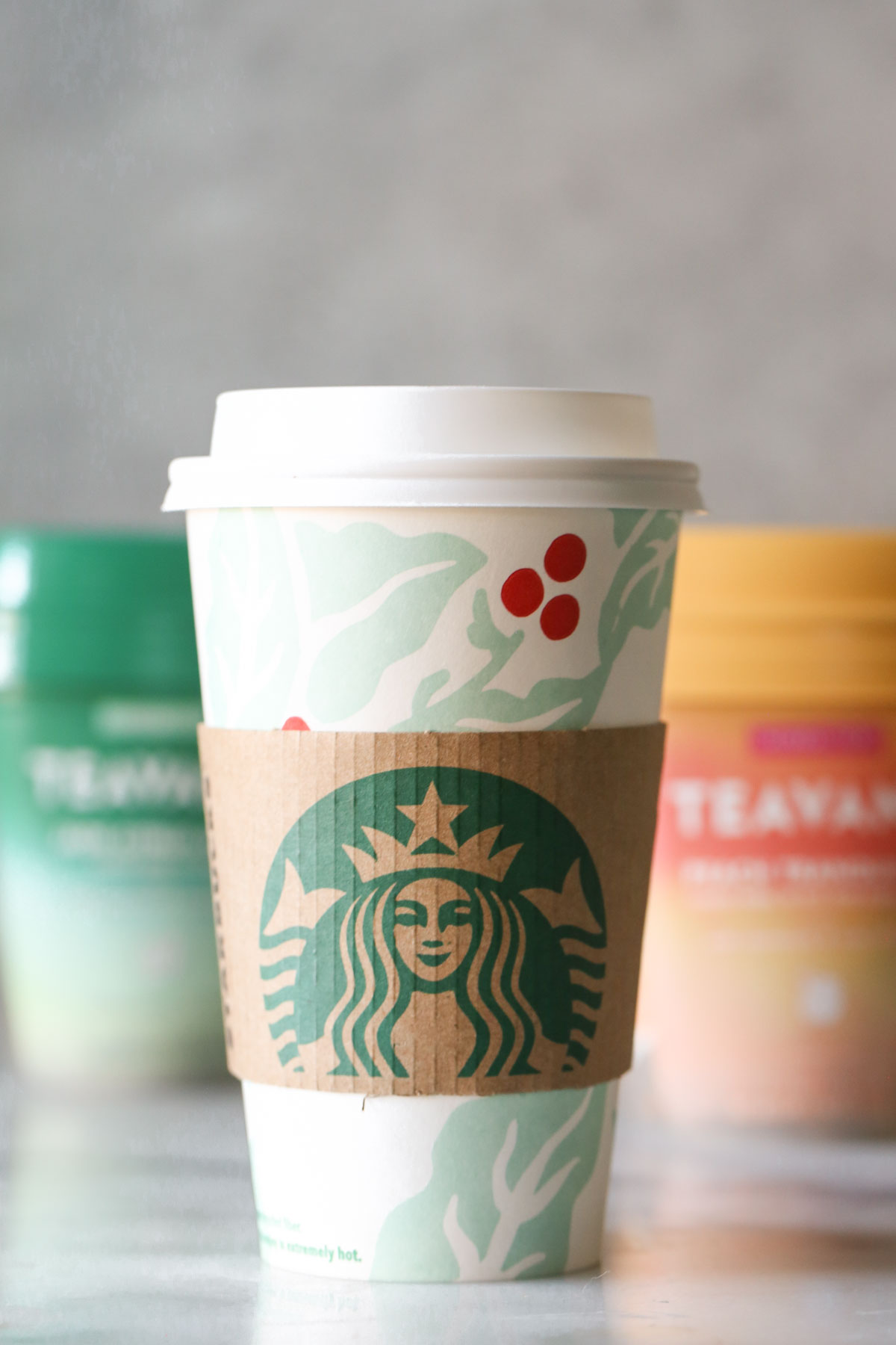 A Starbucks Medicine Ball Tea in a Starbucks hot cup, with the Teavana tea packages in the background.