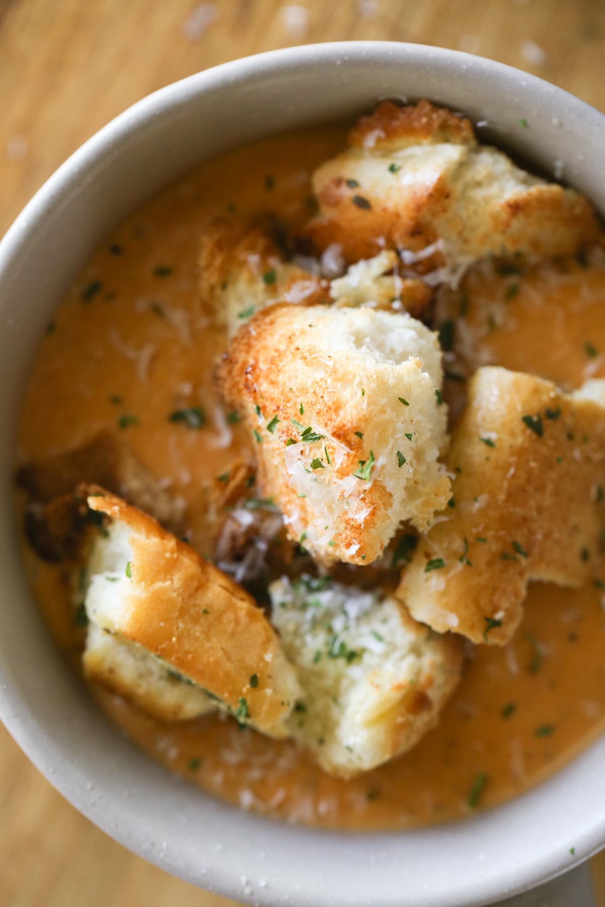 Overhead shot a of bowl of Roasted Vegetable Soup topped with Rustic Buttery Garlic Croutons and fresh Parmesan cheese.
