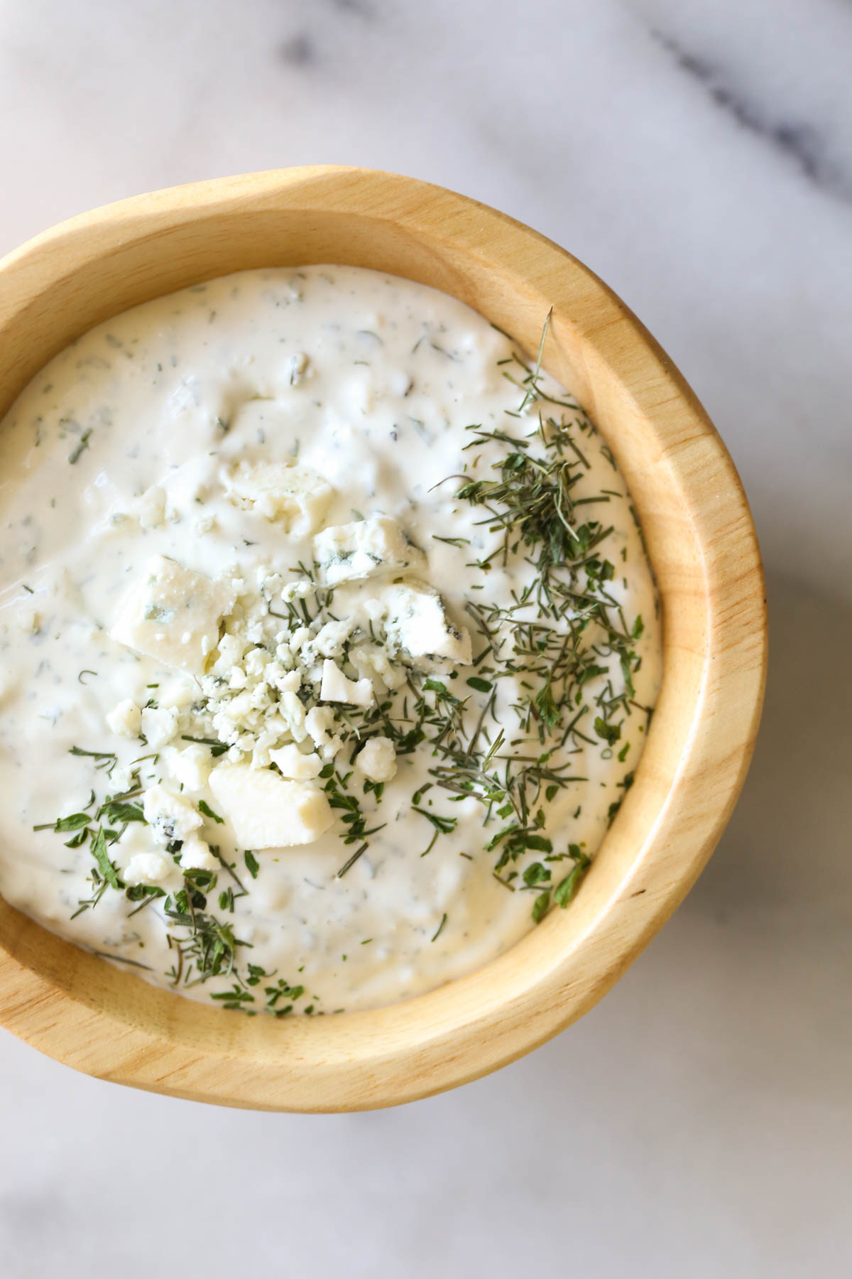 Close up shot of a wood bowl of the blue cheese dressing for the Wedge Style BLT Salad.