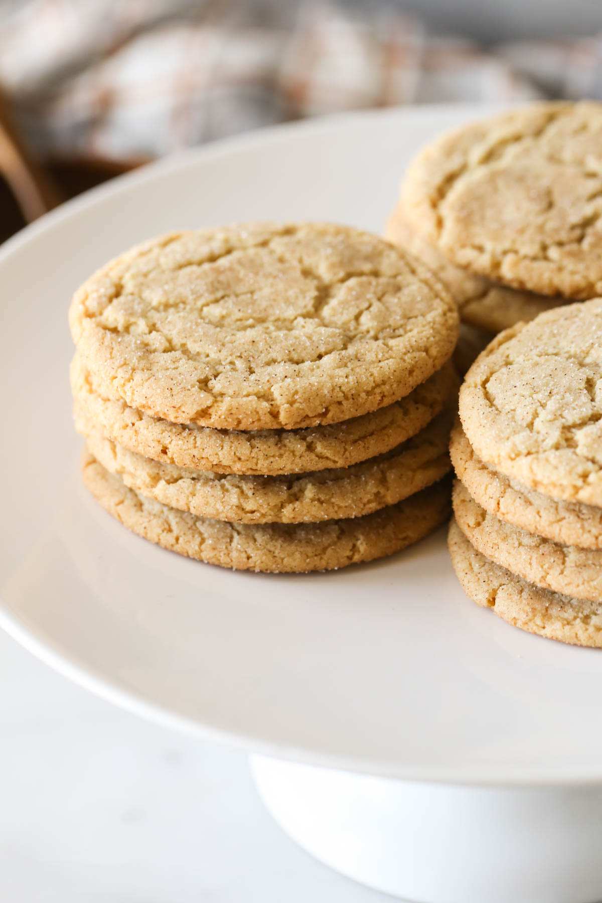 Close up shot of Brown Butter Snickerdoodles in three stacks of four on a white cake stand.