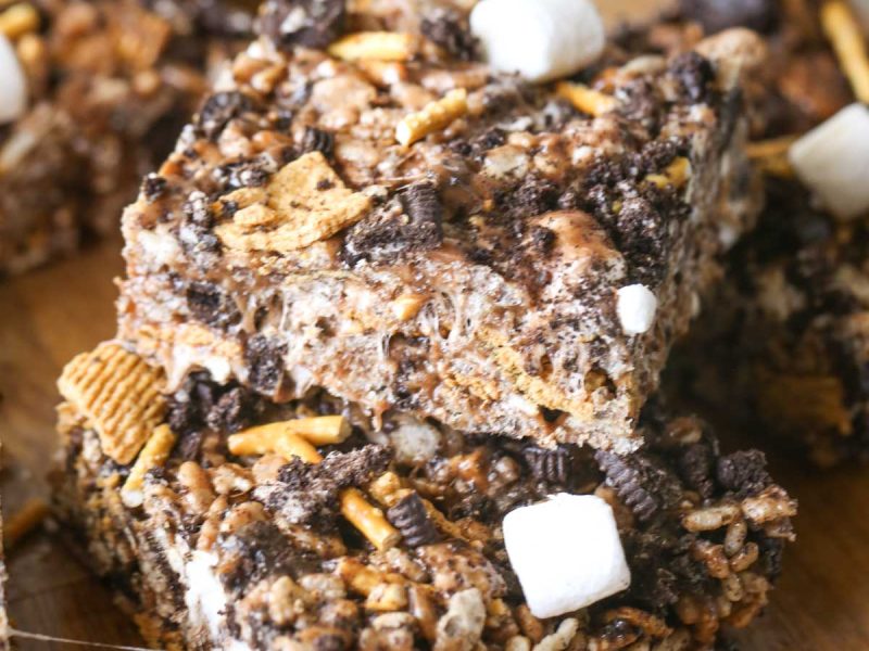 Close up shot of two S'more Bars stacked on a wood cutting board with more bars in the background.