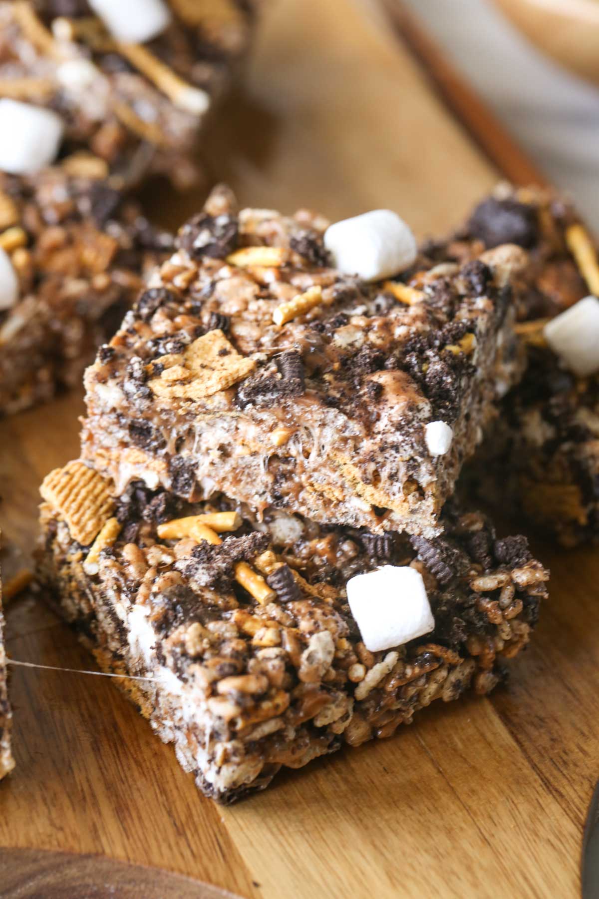 Close up shot of two S'more Bars stacked on a wood cutting board with more bars in the background.