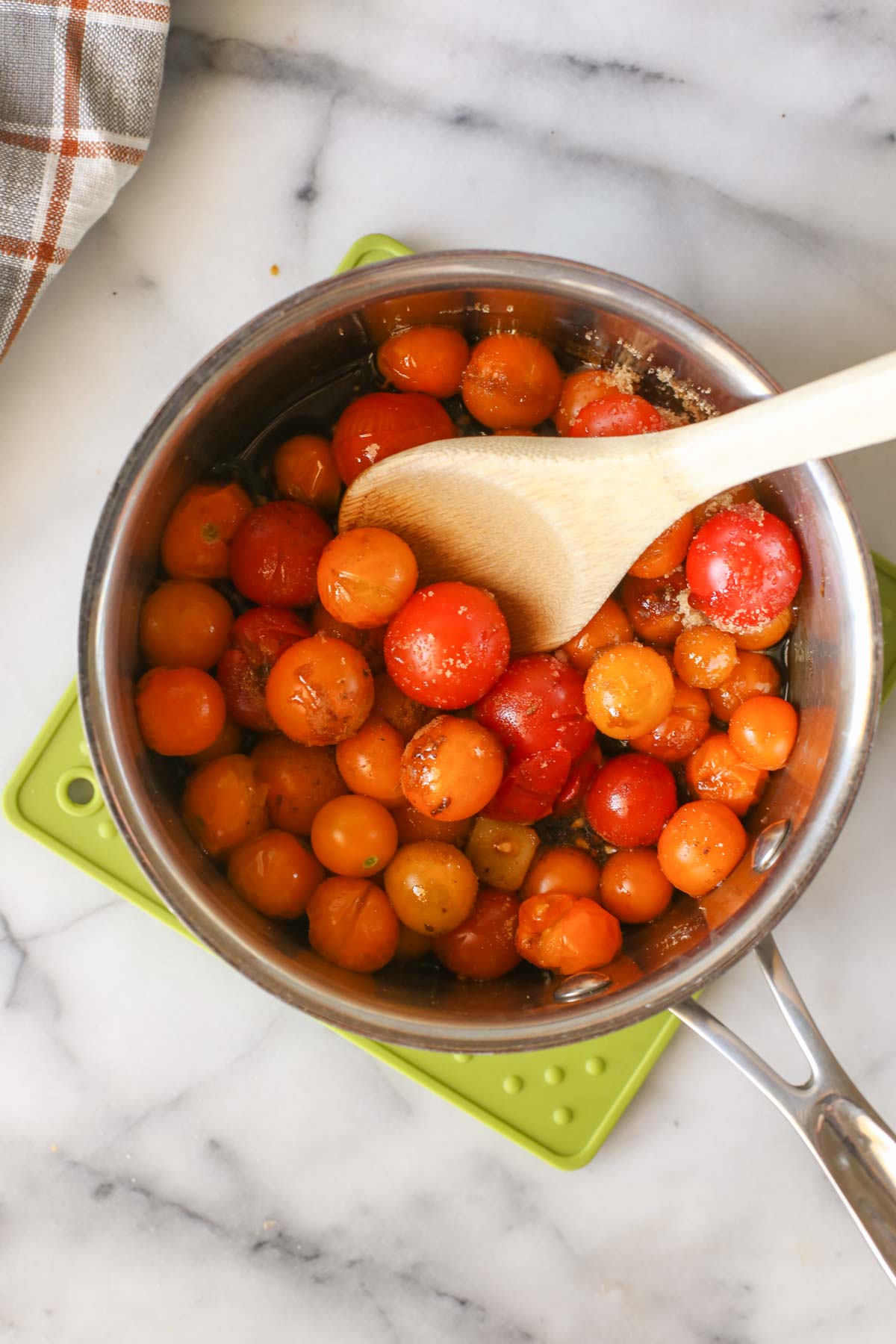 Overhead shot of all the ingredients for Tomato Jam in a saucepan with a wooden spoon in it.  