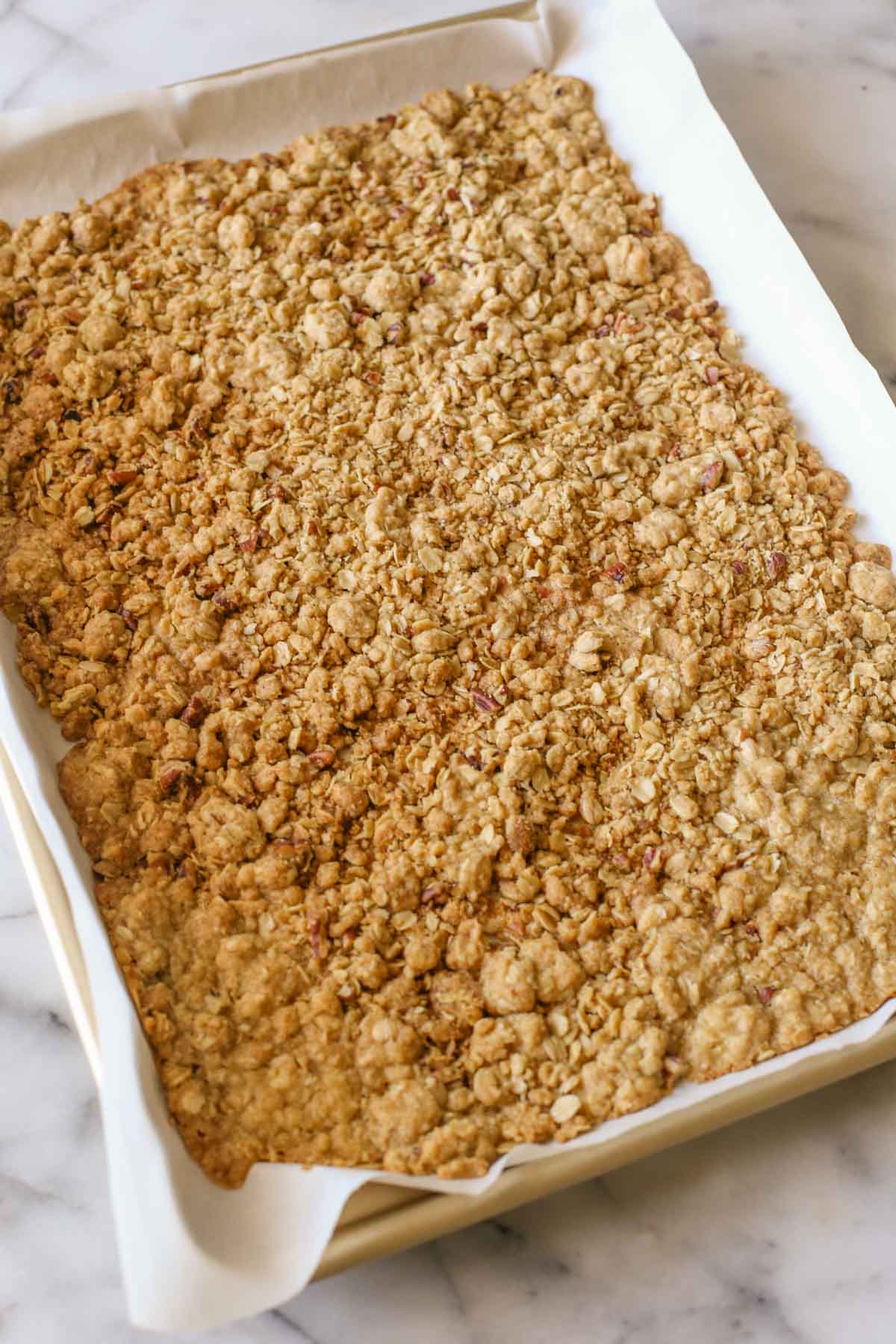 Buttery oat crisp on a parchment paper lined baking sheet.