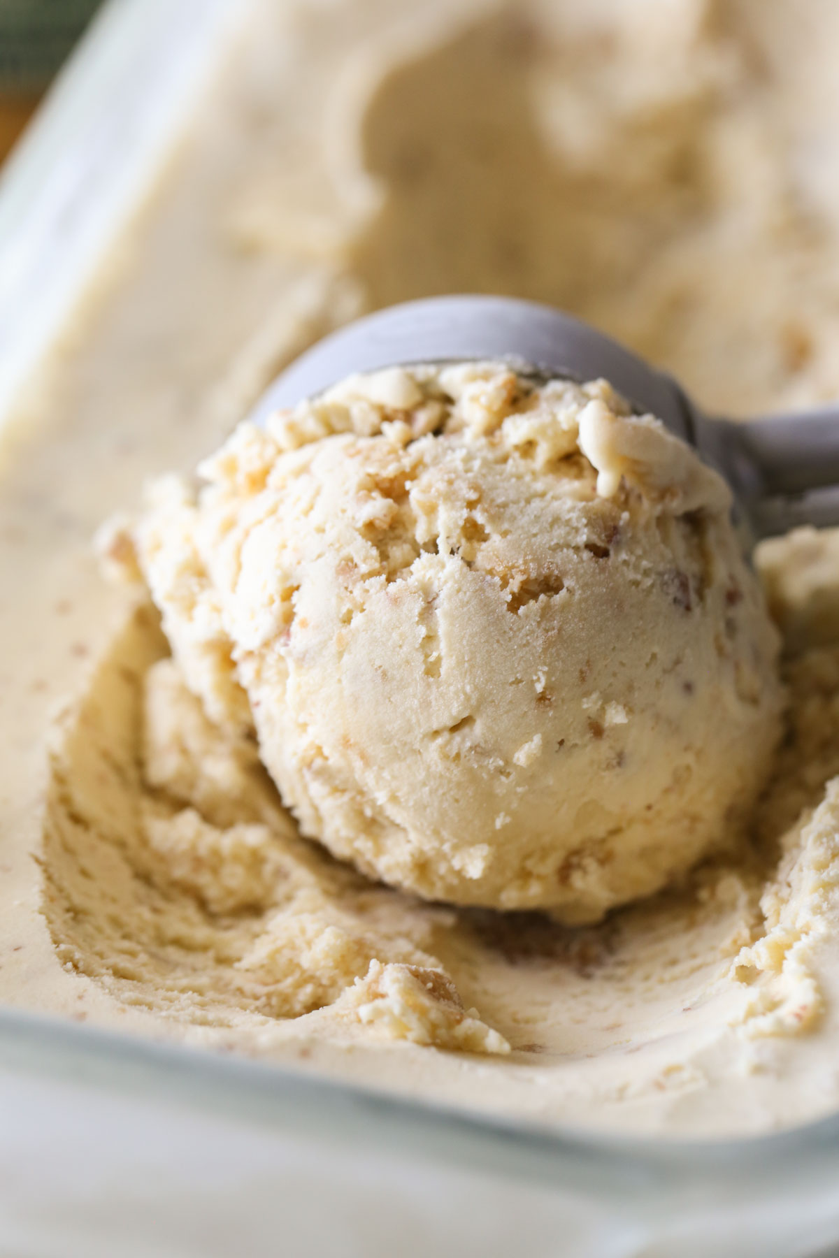 Close up shot of an ice cream scooper full of Cookie Butter Crisp Ice Cream.