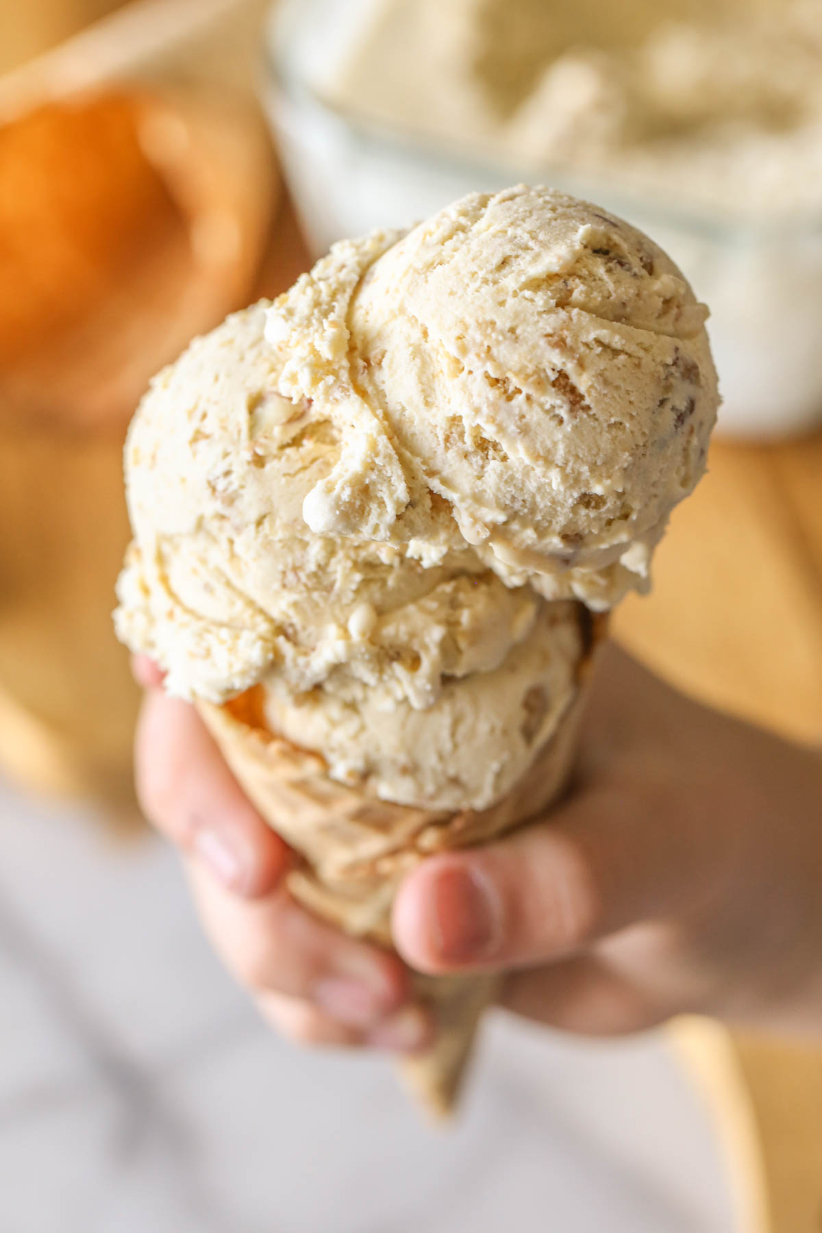 Close up shot of Cookie Butter Crisp Ice Cream in a waffle cone with a hand holding it.