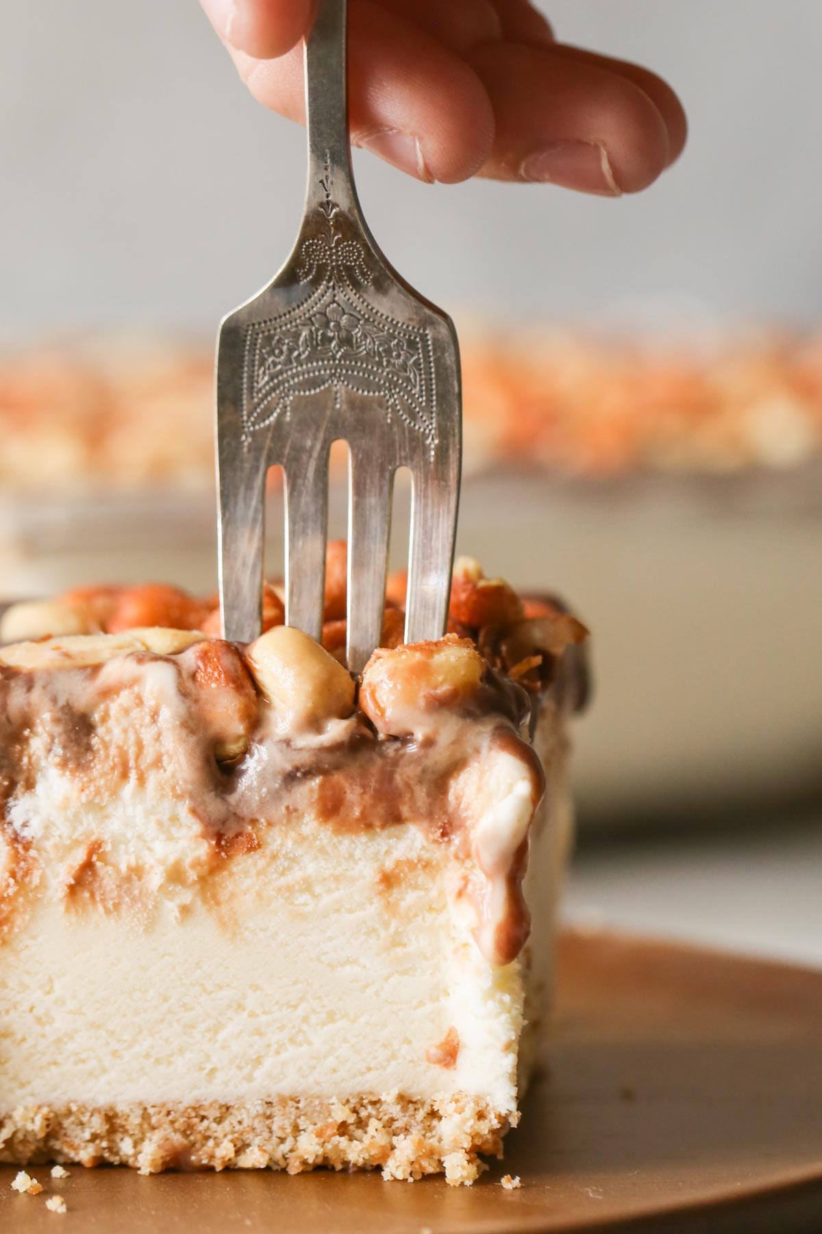 A close up of a fork sticking in a piece of Peanut Buster Ice Cream Dessert. The layers of the Nilla Wafer crust, vanilla ice cream, chocolate fudge, and Spanish peanuts are distinguishable.
