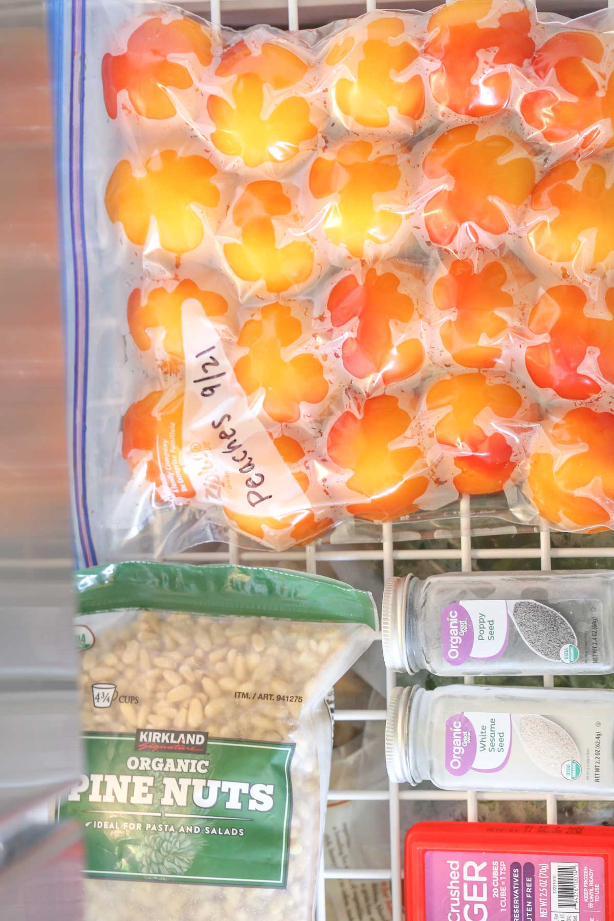 Overhead shot of a Ziploc bag filled with peeled peaches sitting on a rack in the freezer.