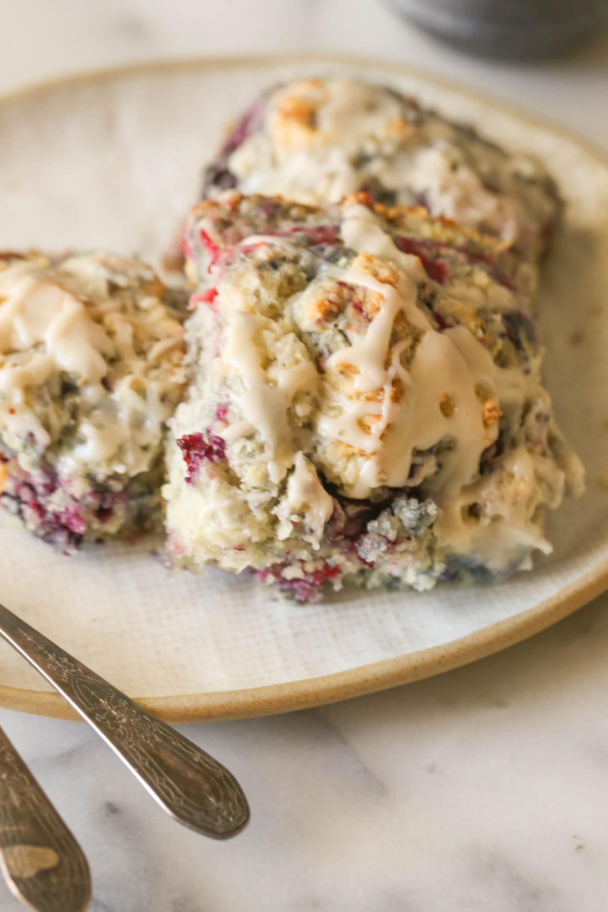 Close up shot of three Glazed Berry Drop Biscuits on a plate.